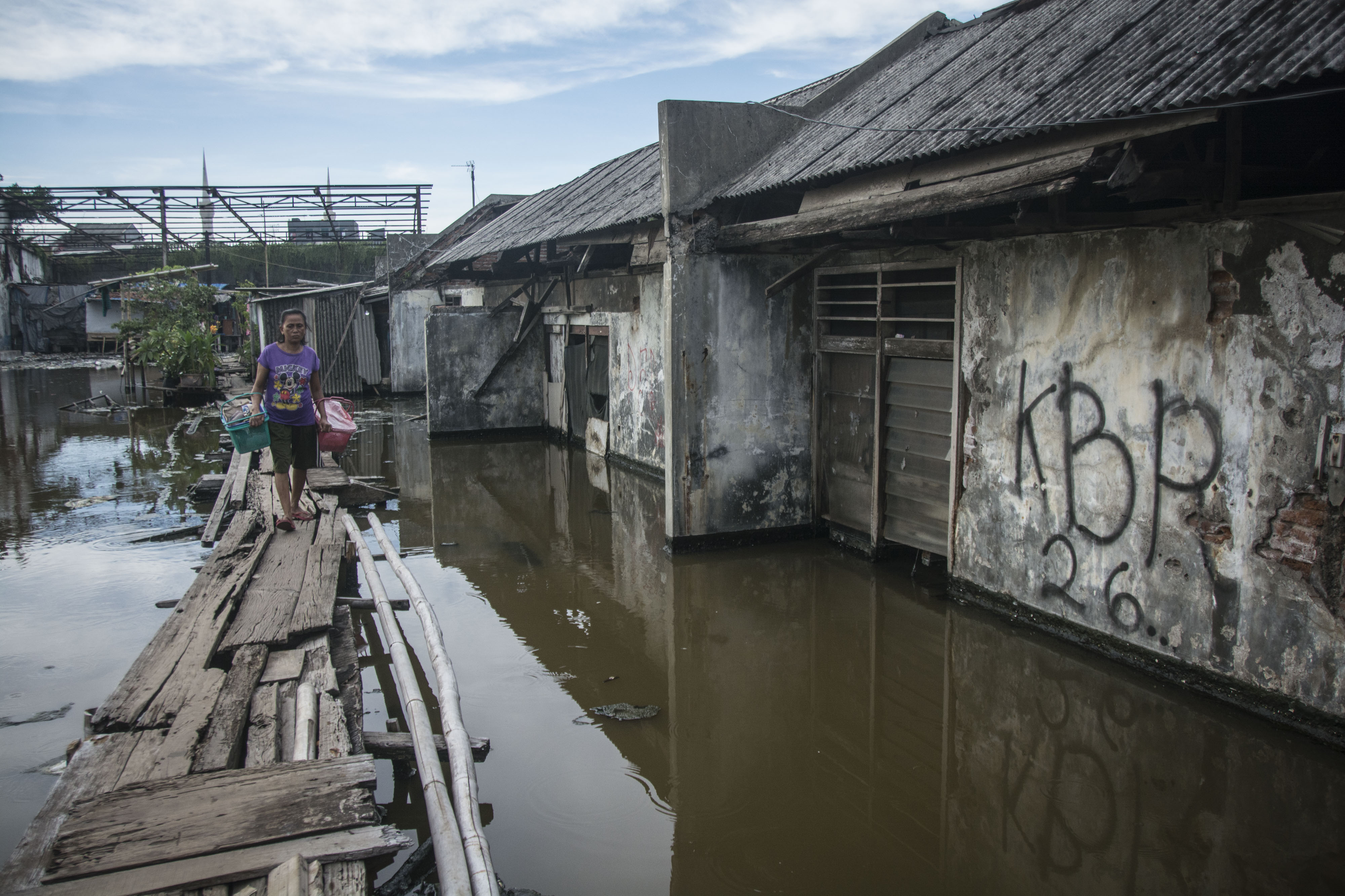 Warga beraktivitas di dekat bangunan yang terendam air laut di kawasan Penjaringan, Jakarta.