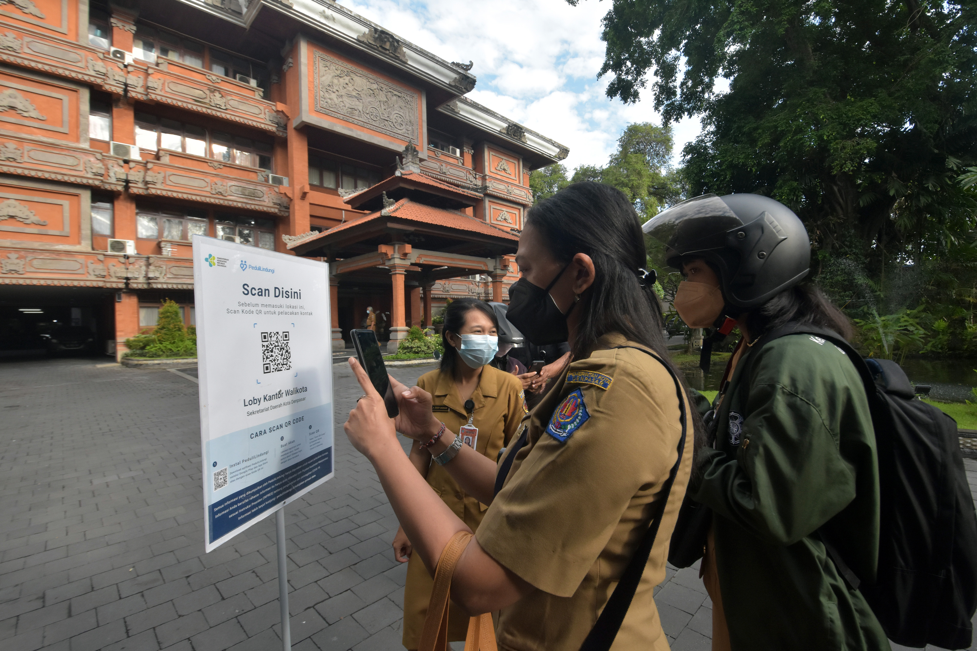 Sejumlah ASN melakukan pemindaian kode batang sertifikat vaksin covid-19 menggunakan aplikasi PeduliLindungi di Bali.