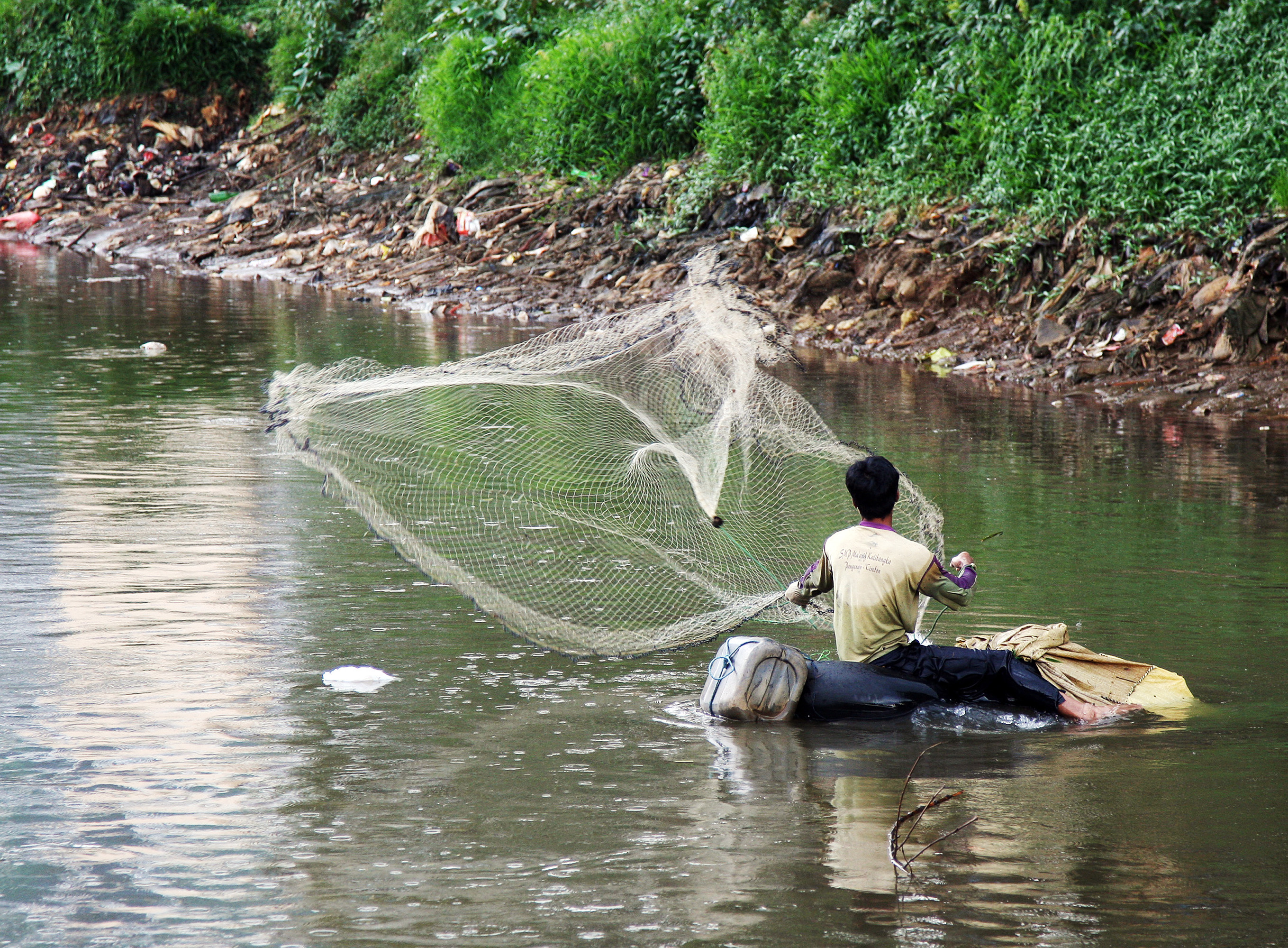  TERCEMAR: Warga menjaring ikan di Kali Ciliwung Jakarta. Pencemaran sampah dan limbah obat-obatan mengancam keanekaragaman hayati di sana.