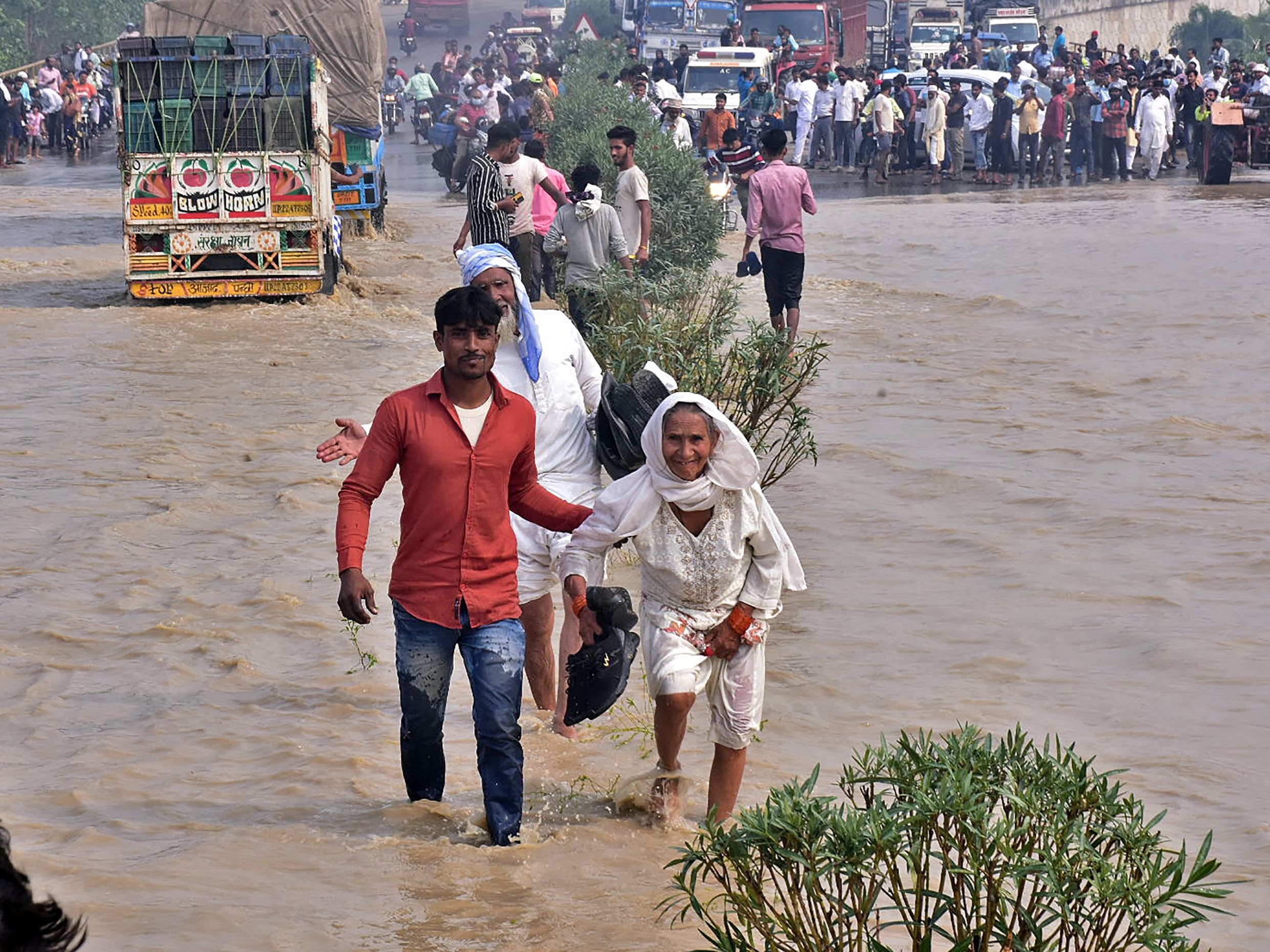 Warga mengarungi jalan raya nasional yang banjir setelah sungai Kosi meluap menyusul hujan lebat, Uttar Pradesh, India, Rabu (20/10).