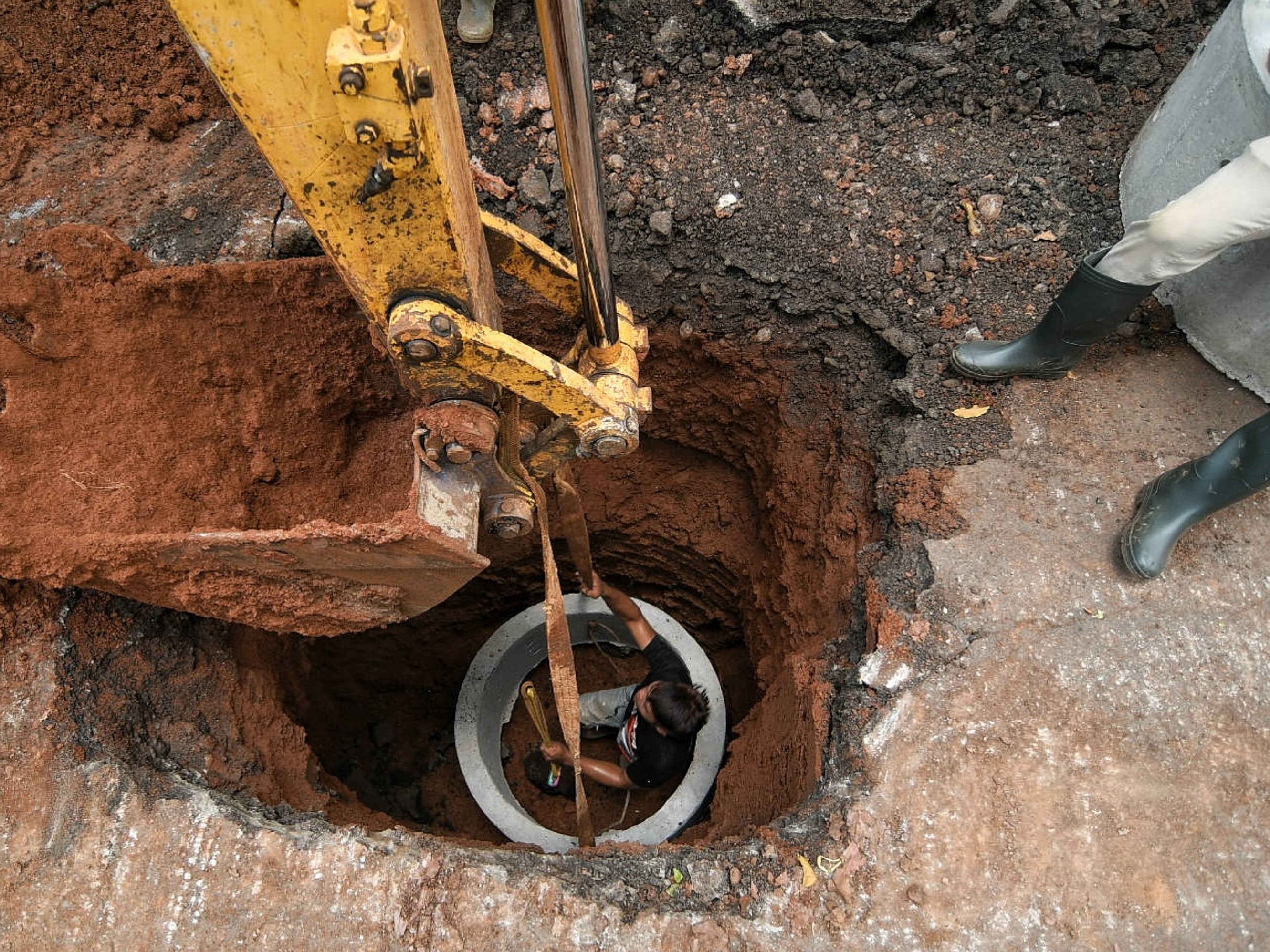 Pekerja menggunakan alat berat saat menyelesaikan pengerjaan sumur resapan di Jalan Mataram Raya, Kebayoran Baru, Jakarta, Selasa (12/10).