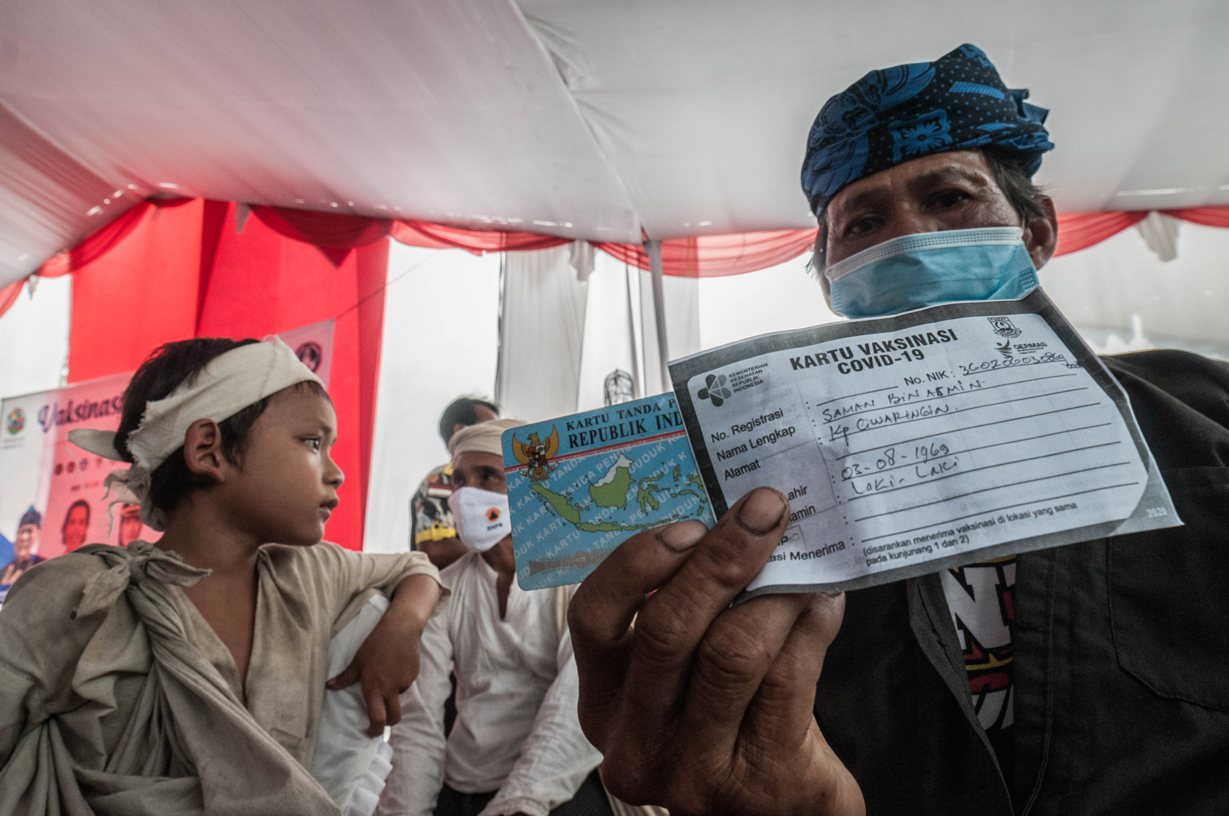 Warga Baduy menunjukkan kartu vaksinasi covid-19 di wilayah Lebak, Banten.