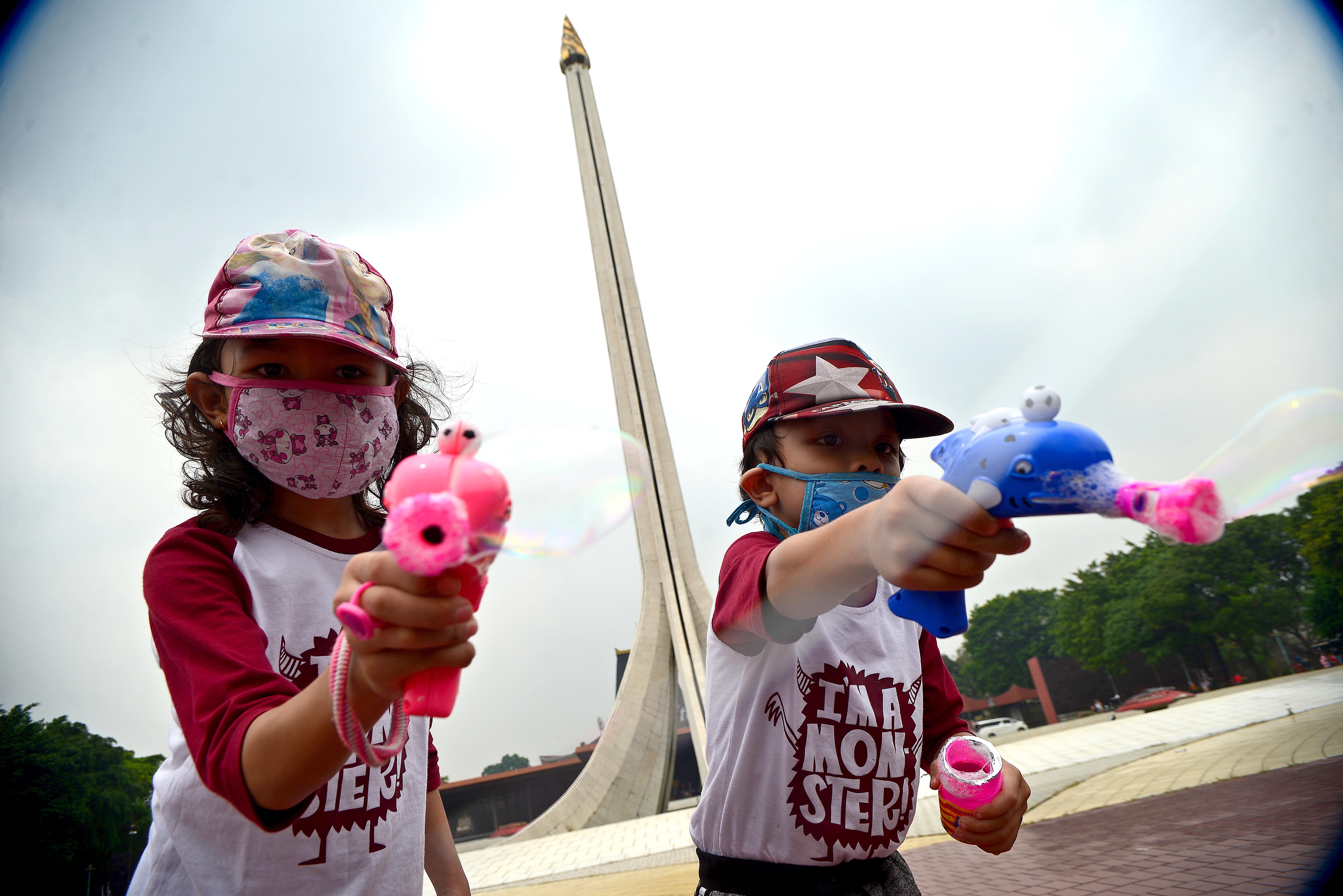 Anak-anak bermain di depan Tugu Api Taman Mini Indonesia Indah (TMII), Jakarta, Minggu (12/09/2021).