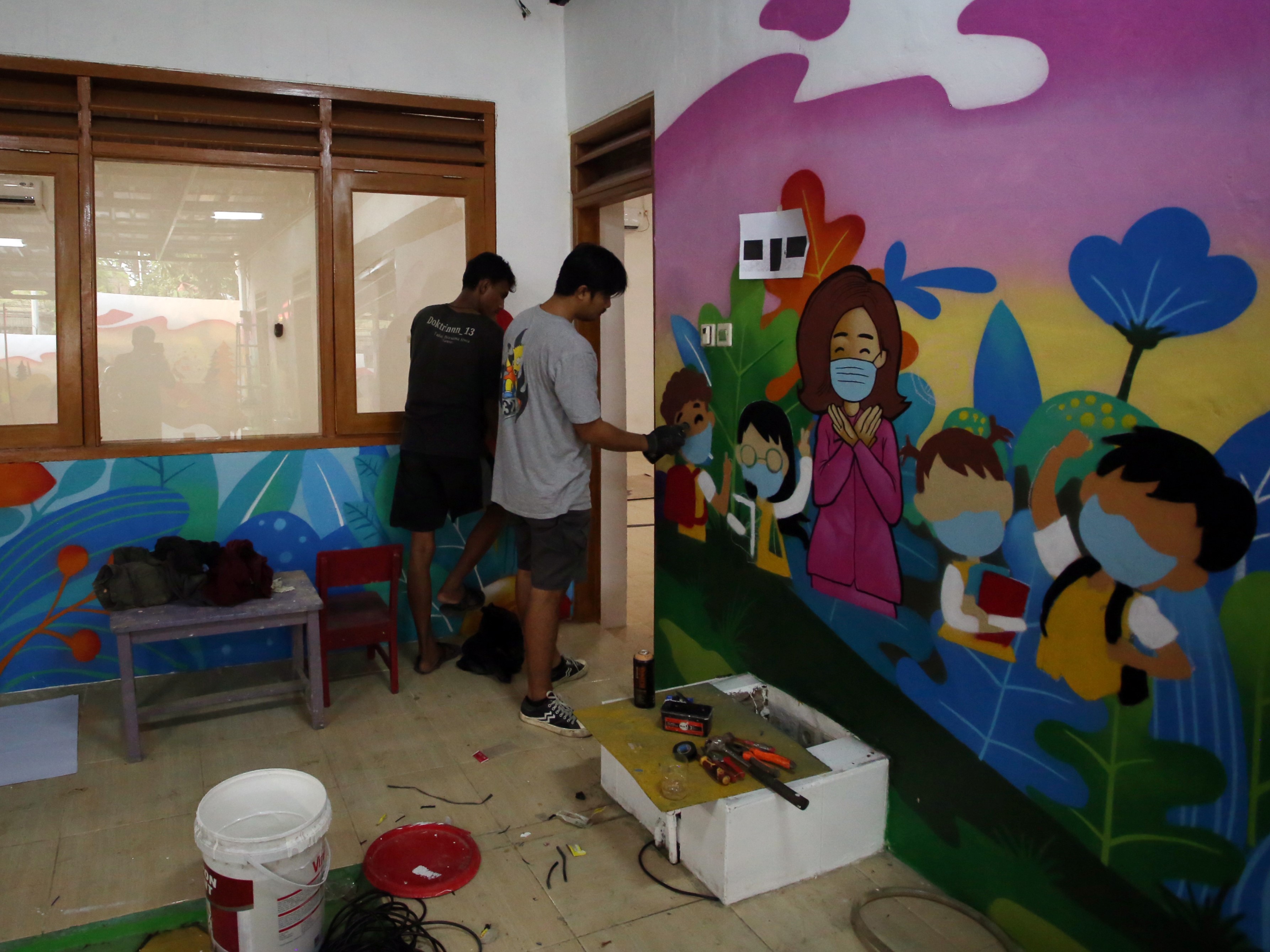 Seniman menyelesaikan pembuatan mural bertema protokol kesehatan di TK Kemala Bhayangkari 51, Tangerang, Banten, Rabu (13/10).