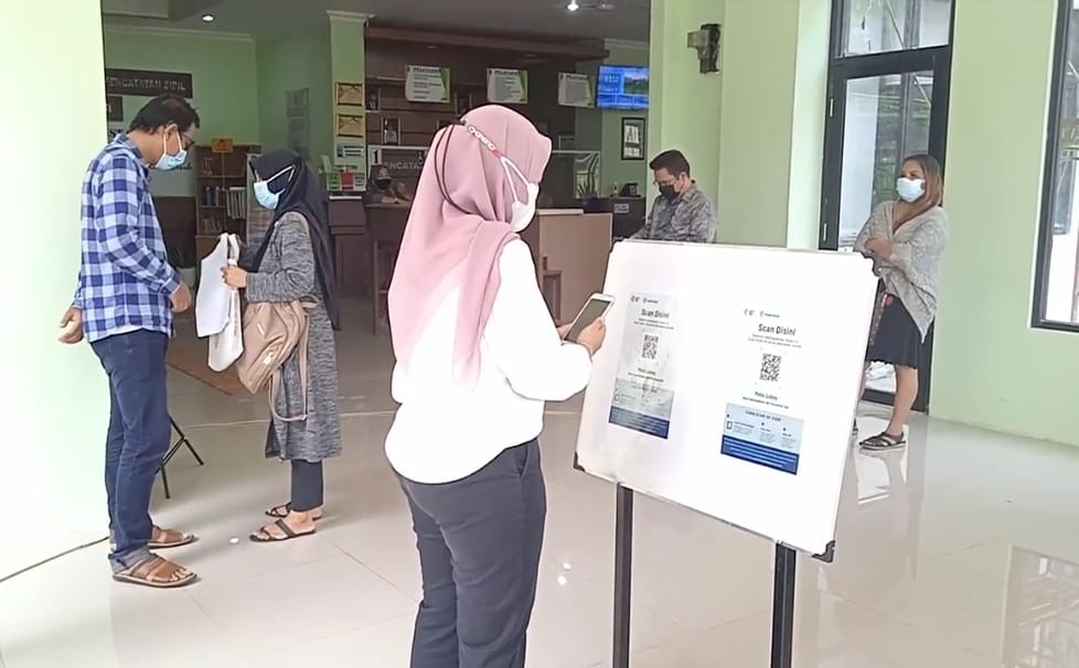 Warga men-scan aplikasi PeduliLindungi di gedung kantor pemerintah Bekasi.