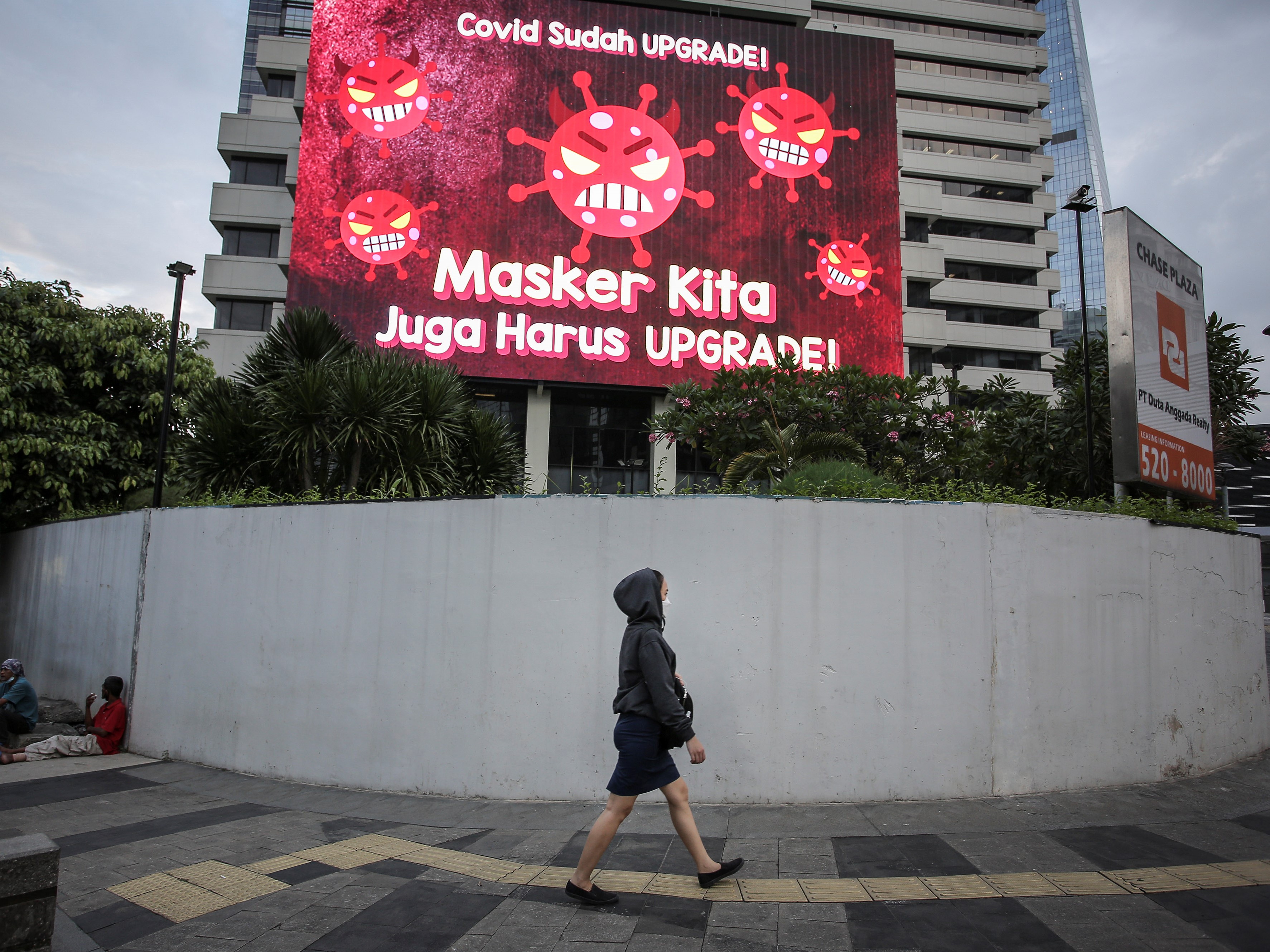 Warga berjalan di depan videotron mengenai protokol kesehatan di kawasan Jalan Jenderal Sudirman, Jakarta, Senin (13/9).
