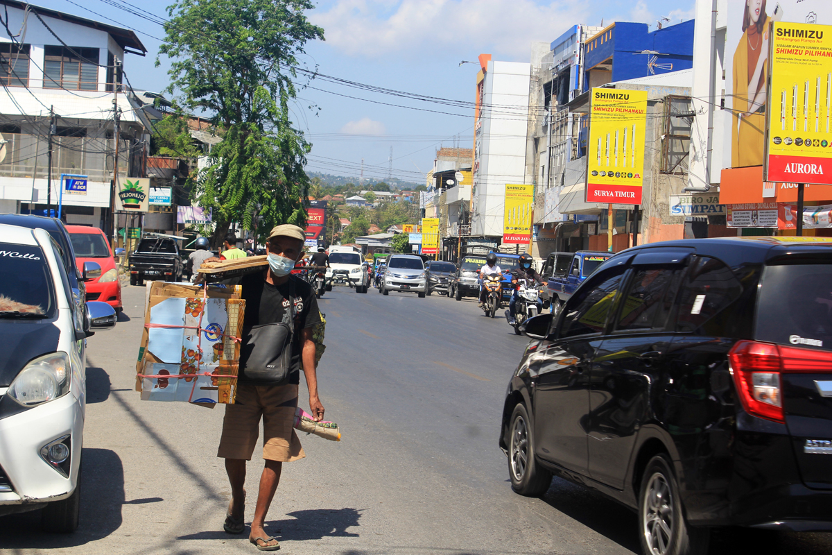 Seorang pemulung mengenakan masker, melintas di Jalan Jenderal Soedirman, Kuanino Kupang, NTT, Senin (26/7)