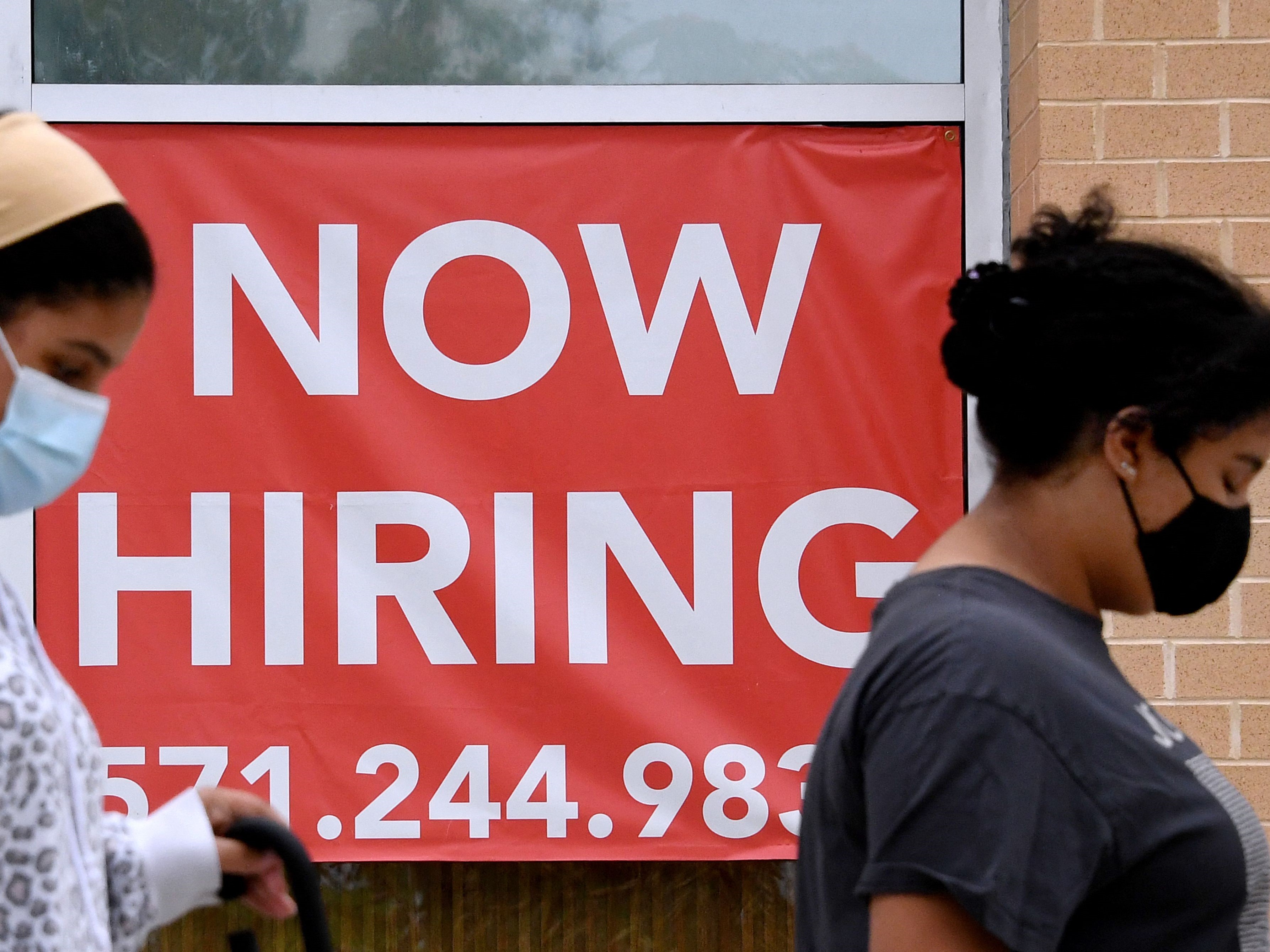 Wanita berjalan melewati informasi lowongan pekerjaan di luar toko di Arlington, Virginia, AS.