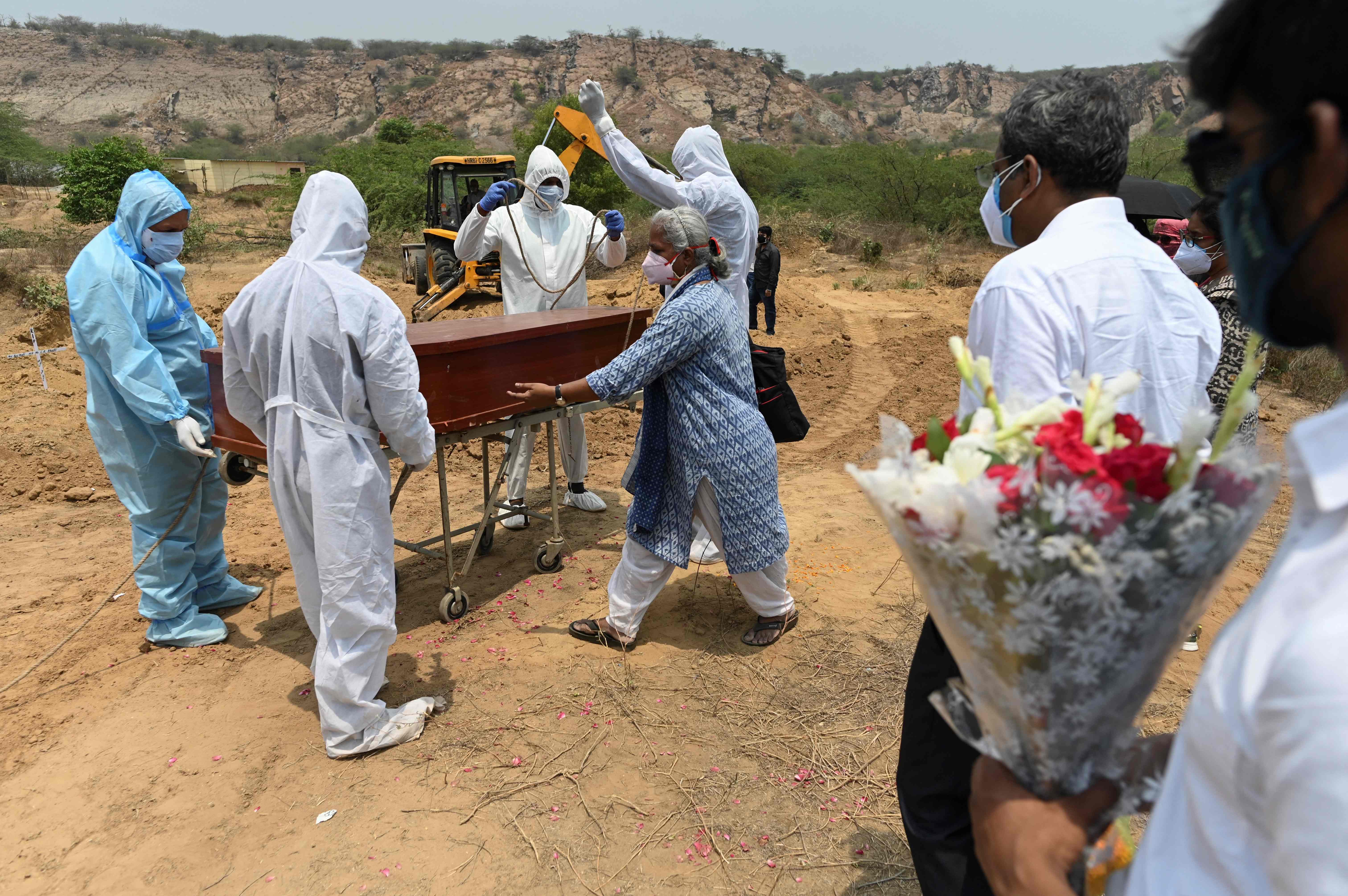 Petugas mengenakan APD akan memakamkan jenazah pasien covid-19 di Faridabad, India.