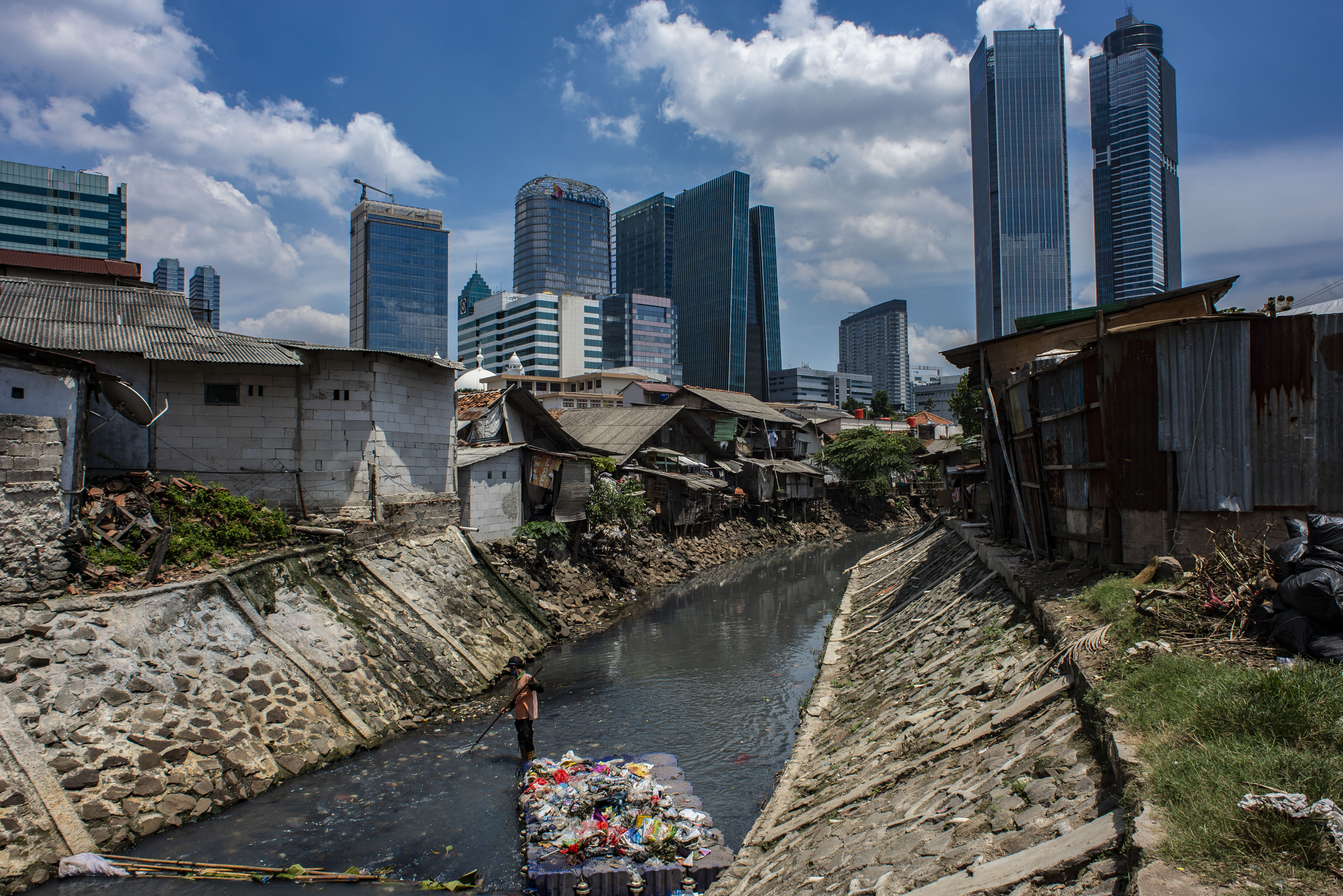 Petugas PPSU saat membersihkan sampah yang terbawa aliran sungai di Jakarta.