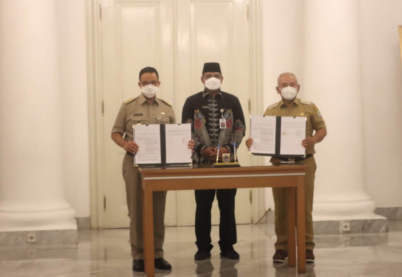 Gubernur DKI Jakarta Anies Baswedan (kiri) dan Wali Kota Bekasi Rahmat Effendi memperlihatkan perjanjian kerjasama pengelolaan TPST Bantarge