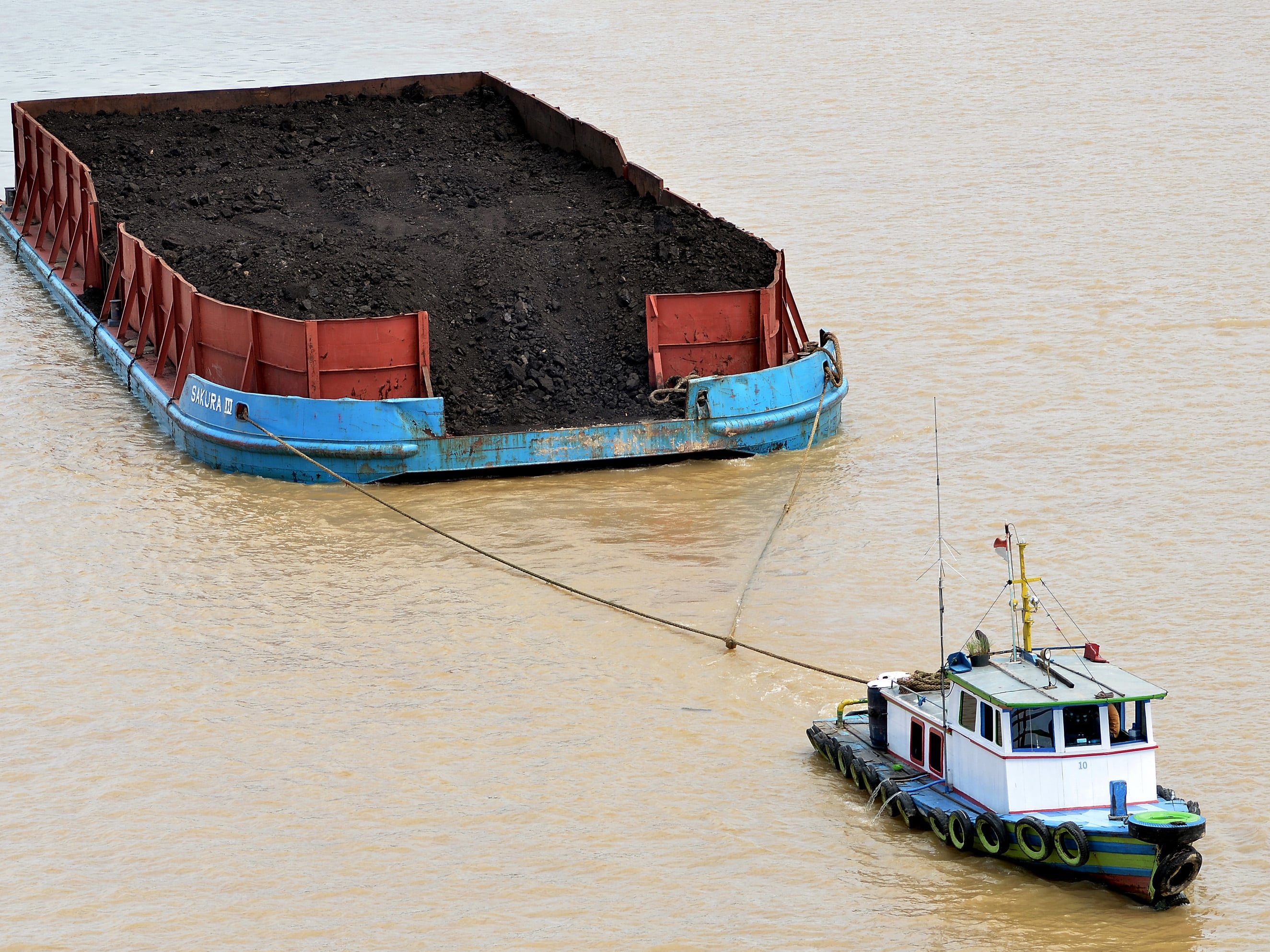 Kapal Tongkang pembawa batubara melintasi aliran Sungai Batanghari di Muaro Jambi, Jambi.