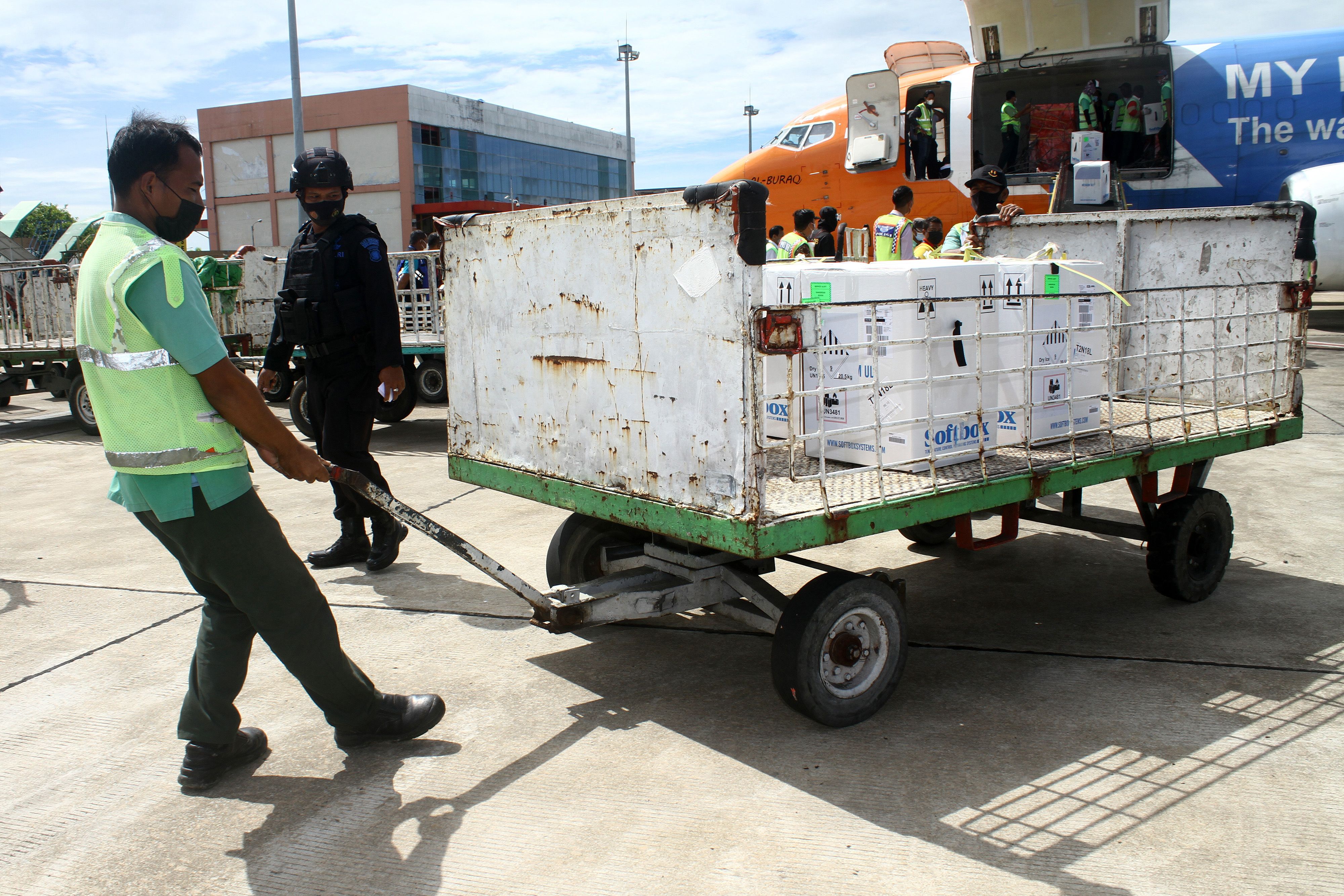 Petugas menarik kereta bermuatan kotak vaksin Pfizer di Bandara Supadio, Kalimantan Barat.