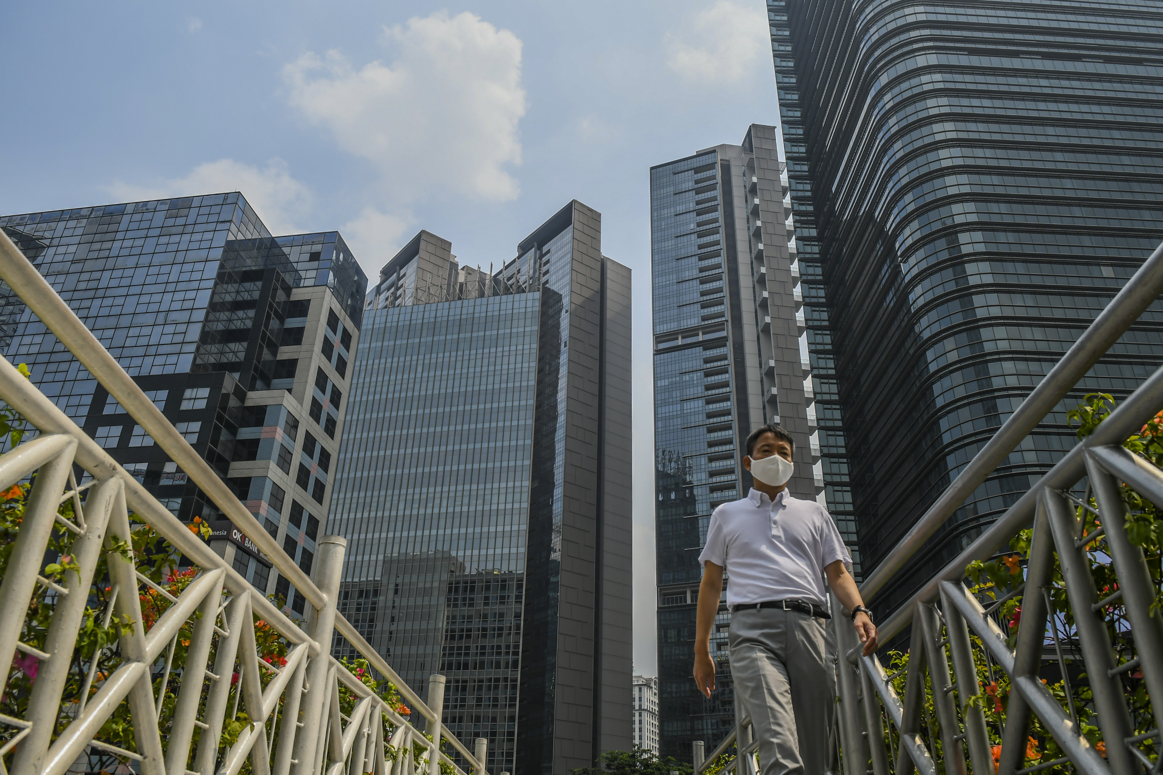 Warga berjalan dengan latar gedung bertingkat di kawasan Sudirman, Jakarta.