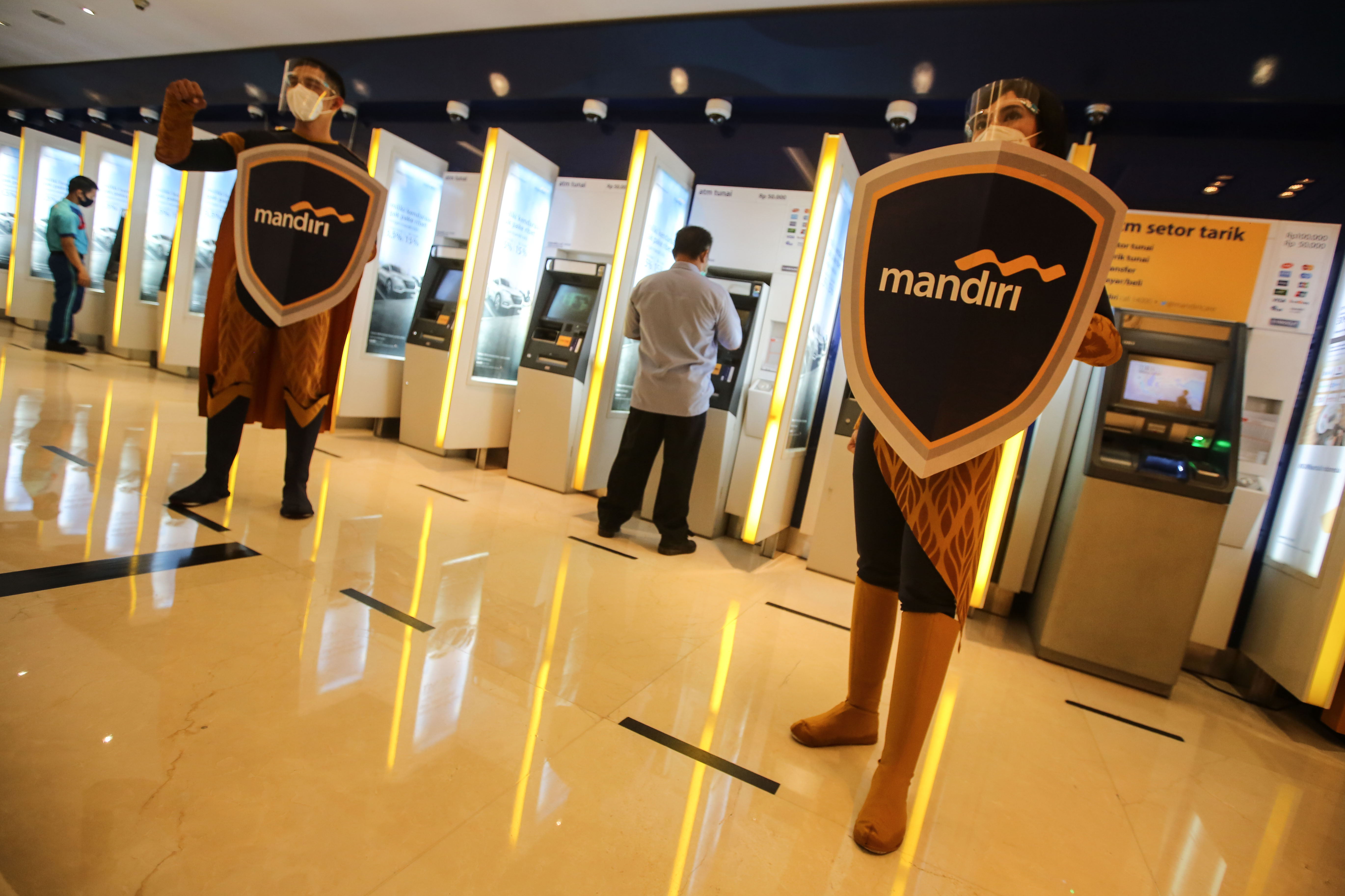 Maskot Mandiri Covid-19 Rangers berdiri di sekitar ATM yang berlokasi di Jakarta.