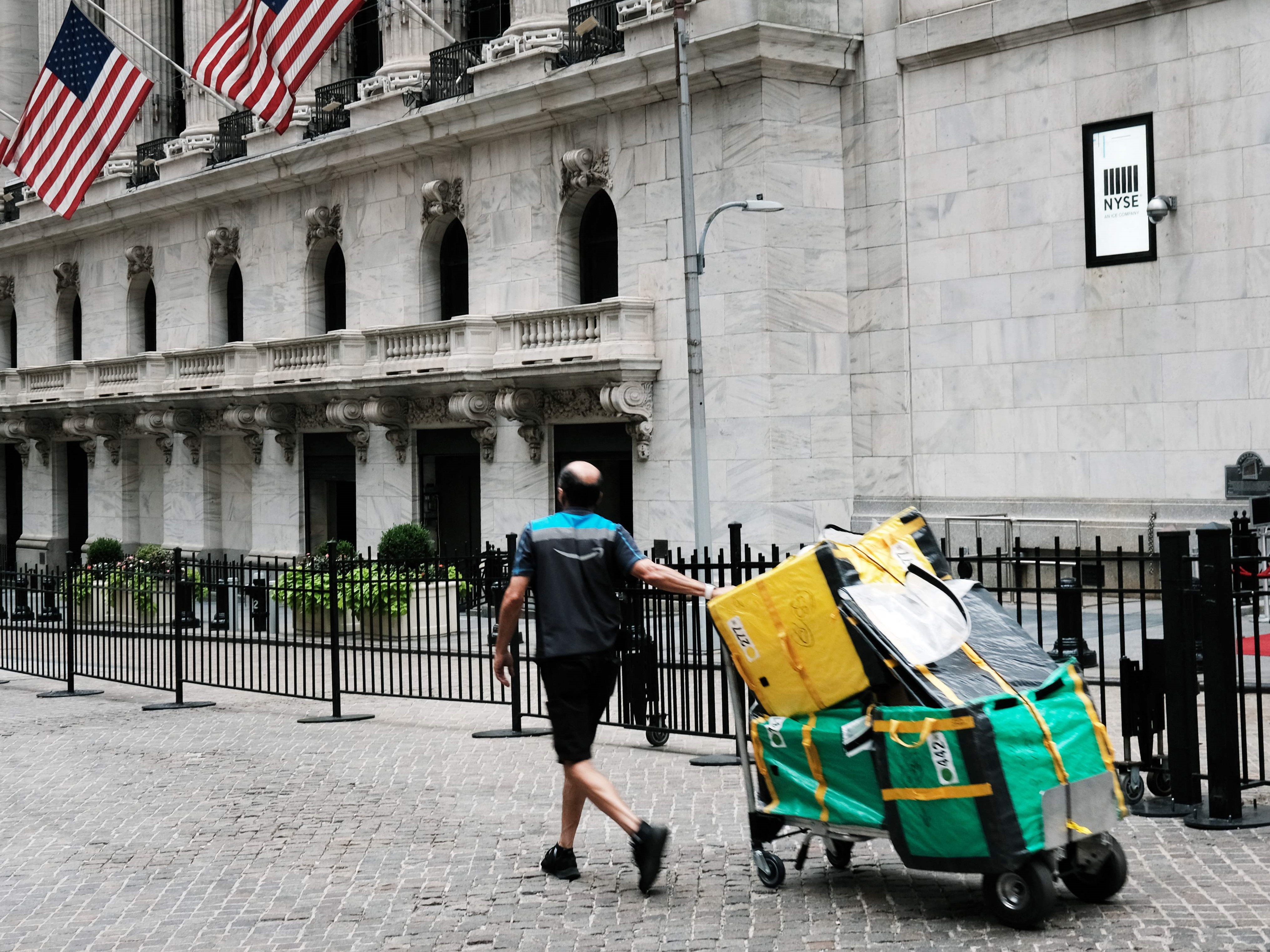 Seorang pekerja pengiriman berjalan di dekat New York Stock Exchange (NYSE) di New York City.