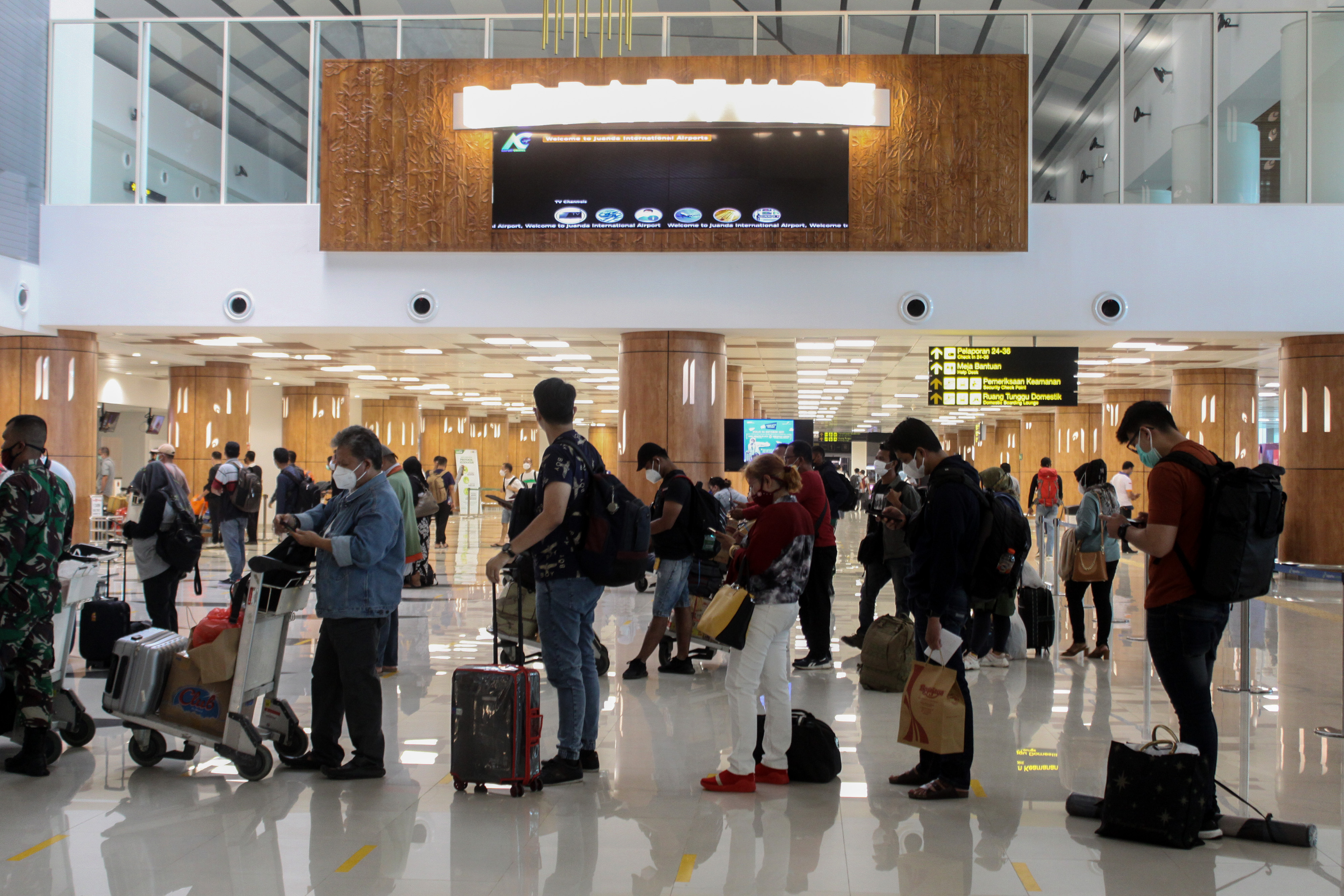 Calon penumpang pesawat antre di area lapor diri sebelum melakukan penerbangan di Bandara Internasional Juanda Surabaya, Jawa Timur.