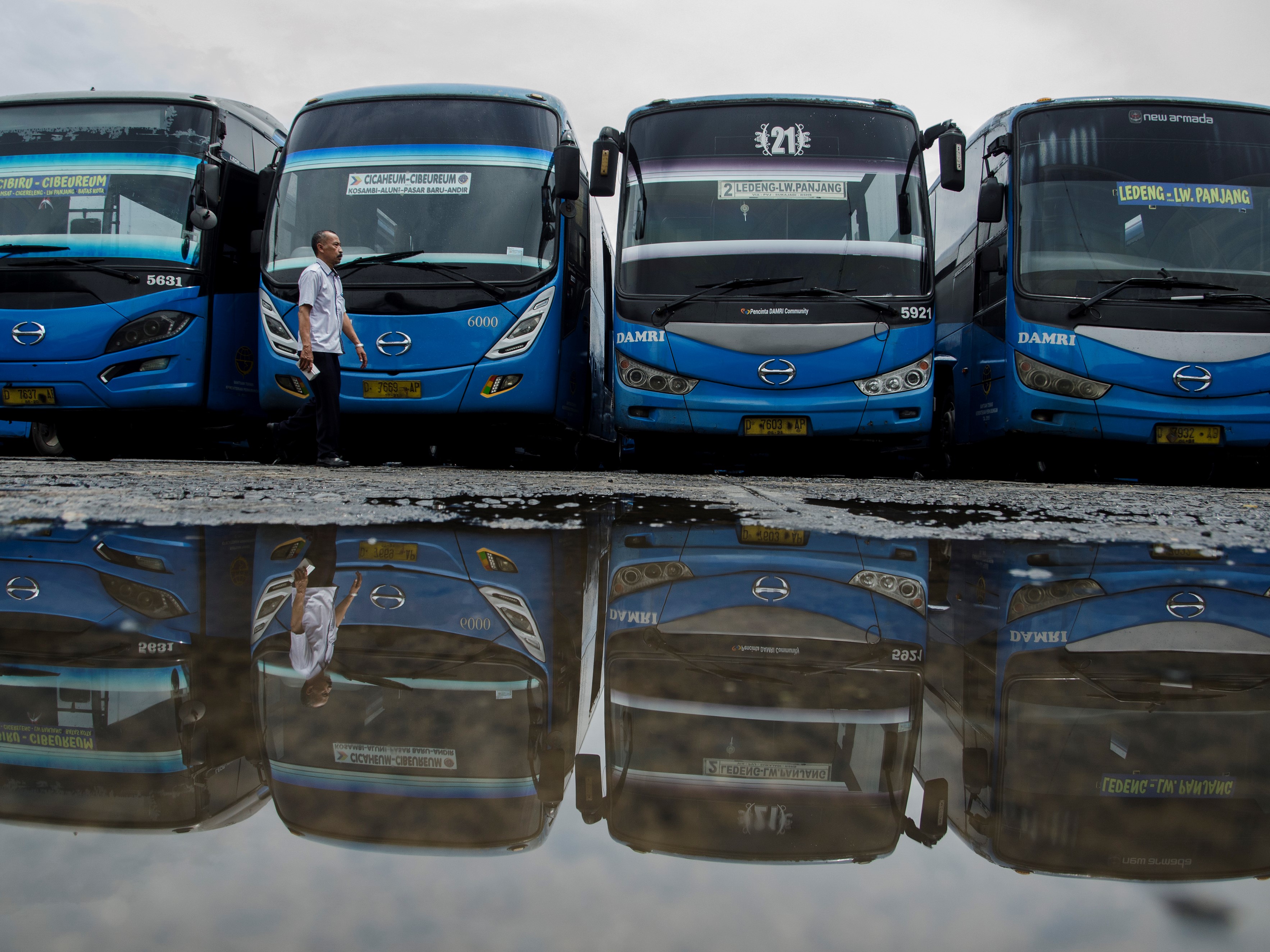 Sopir berjalan di depan bus yang tidak beroperasi di pool (pangkalan) Bus Damri, Bandung, Jawa Barat, Kamis (28/10).