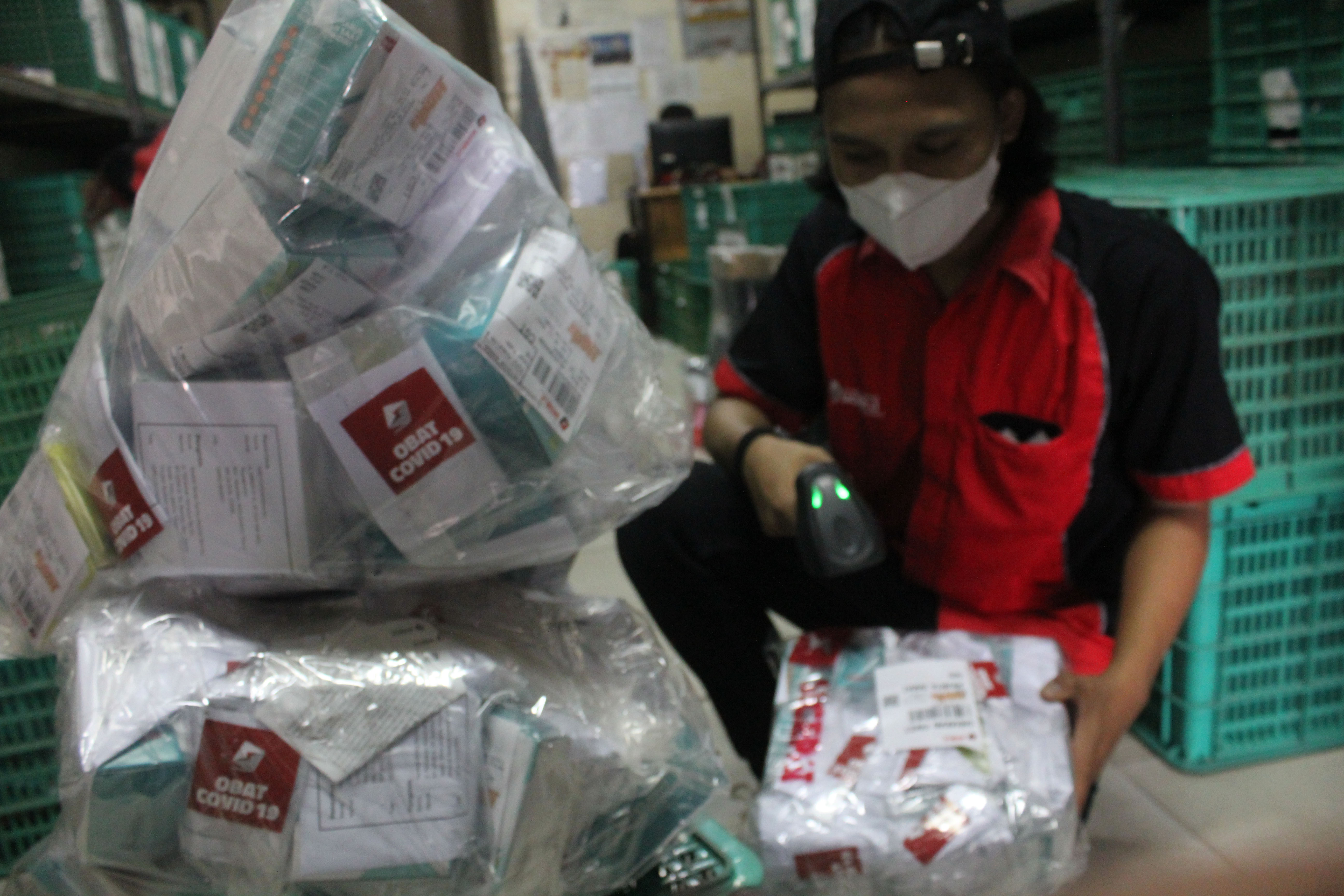 Ilustrasi pekerja ekspedisi mengecek paket obat covid-19 yang akan didistribusikan.