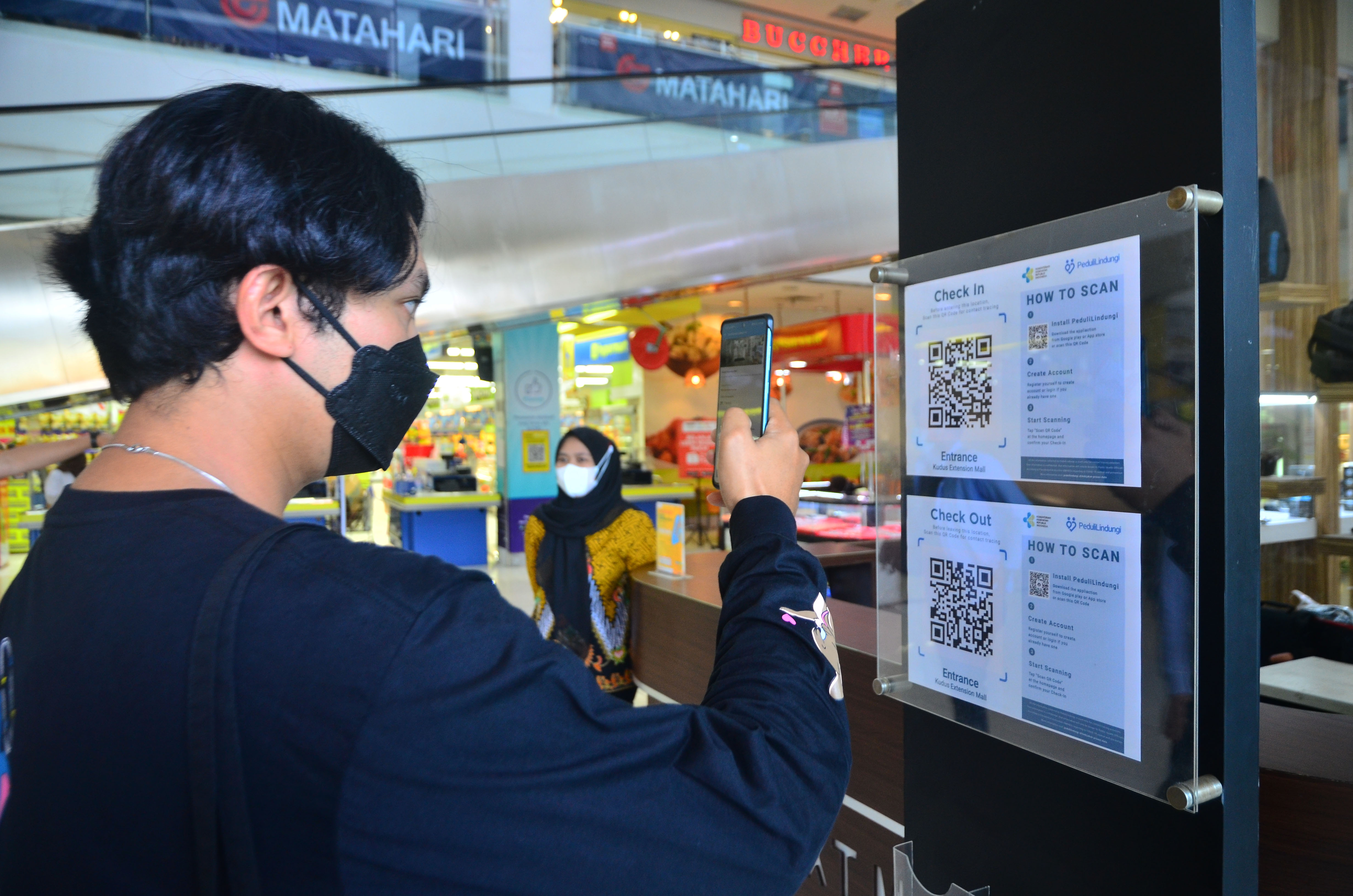 Pengunjung memindai kode batang (QR Code) melalui aplikasi PeduliLindungi sebelum memasuki pusat perbelanjaan di Kudus, Jawa Tengah.