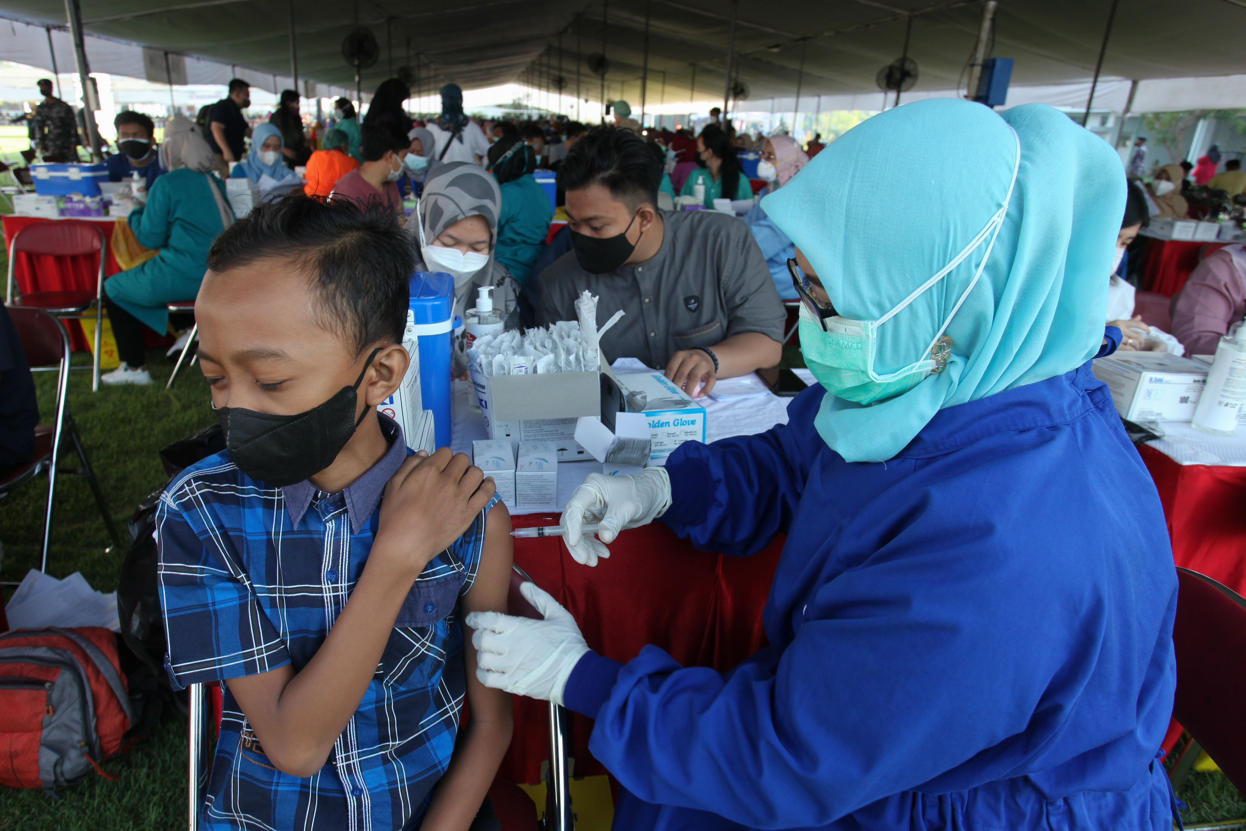 Petugas menyuntikkan vaksin covid-19 kepada seorang anak di Lapangan Thor, Surabaya, Jawa Timur, Kamis (30/9/2021)
