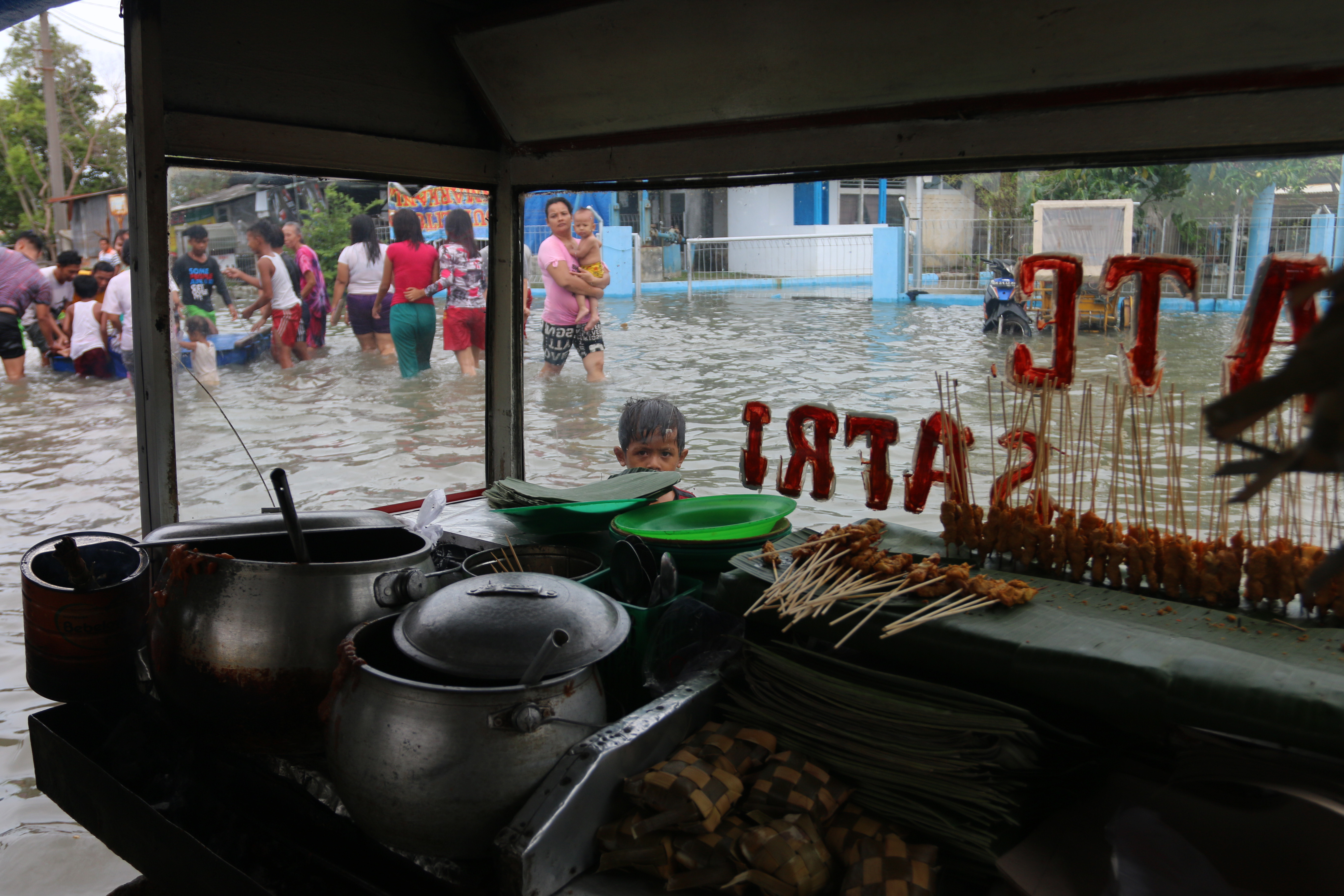 BANJIR ROB: Warga melintasi genangan air akibat banjir rob di Belawan. Banjir rob merendam ribuan rumah warga di kawasan tersebut.