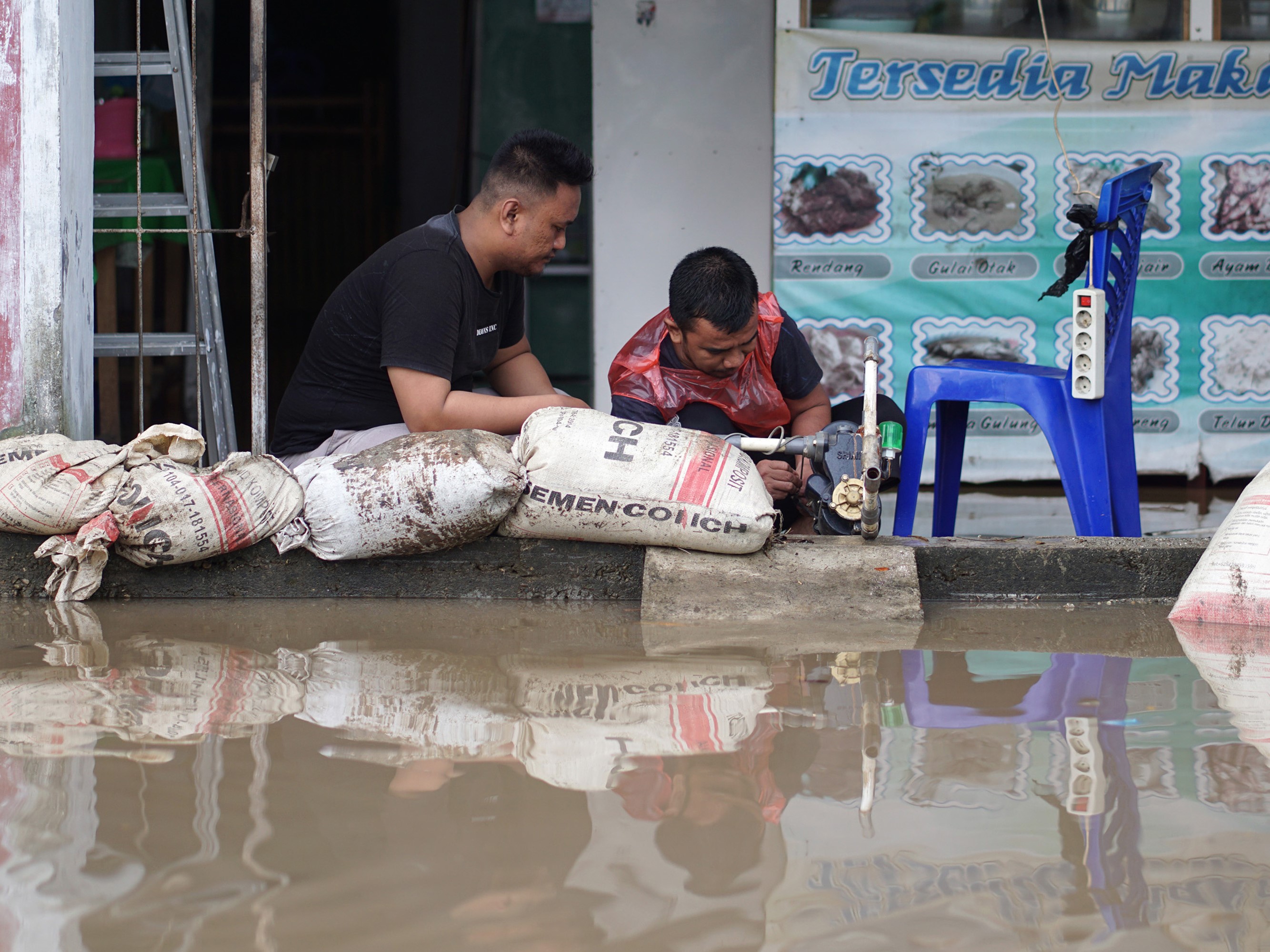 Warga memasang pompa untuk mengeluarkan air dari warung makan miliknya saat banjir di Limboto, Kabupaten Gorontalo, Gorontalo, Jumat (1/10).