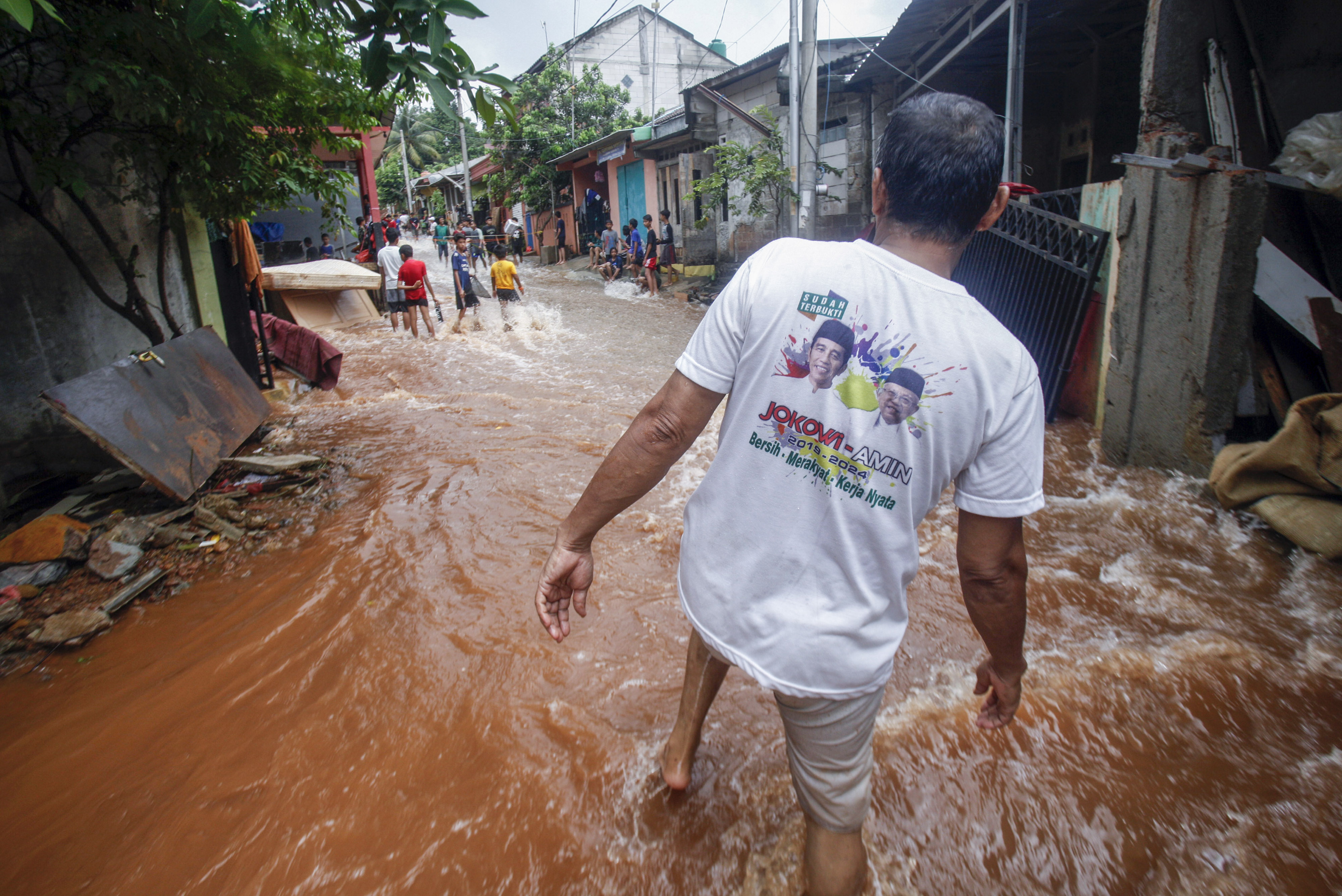 Warga melintasi jalan yang terendam banjir di Perumahan Puri Citayam Permai 2, Bojong Gede, Kabupaten Bogor.