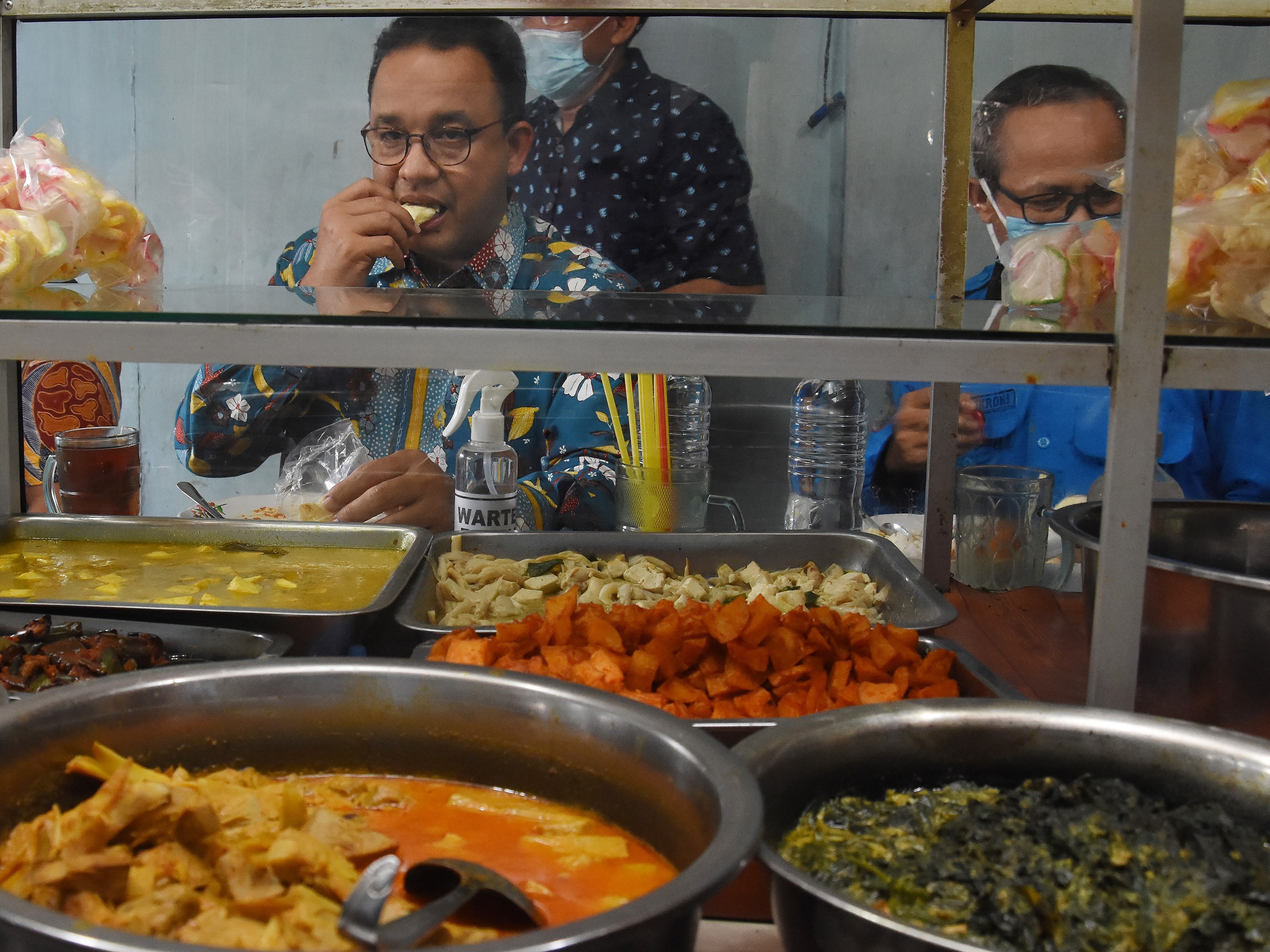 Gubernur DKI Jakarta Anies Baswedan menikmati makan siang di salah satu warteg yang menjadi sentra penyaluran bantuan pangan.