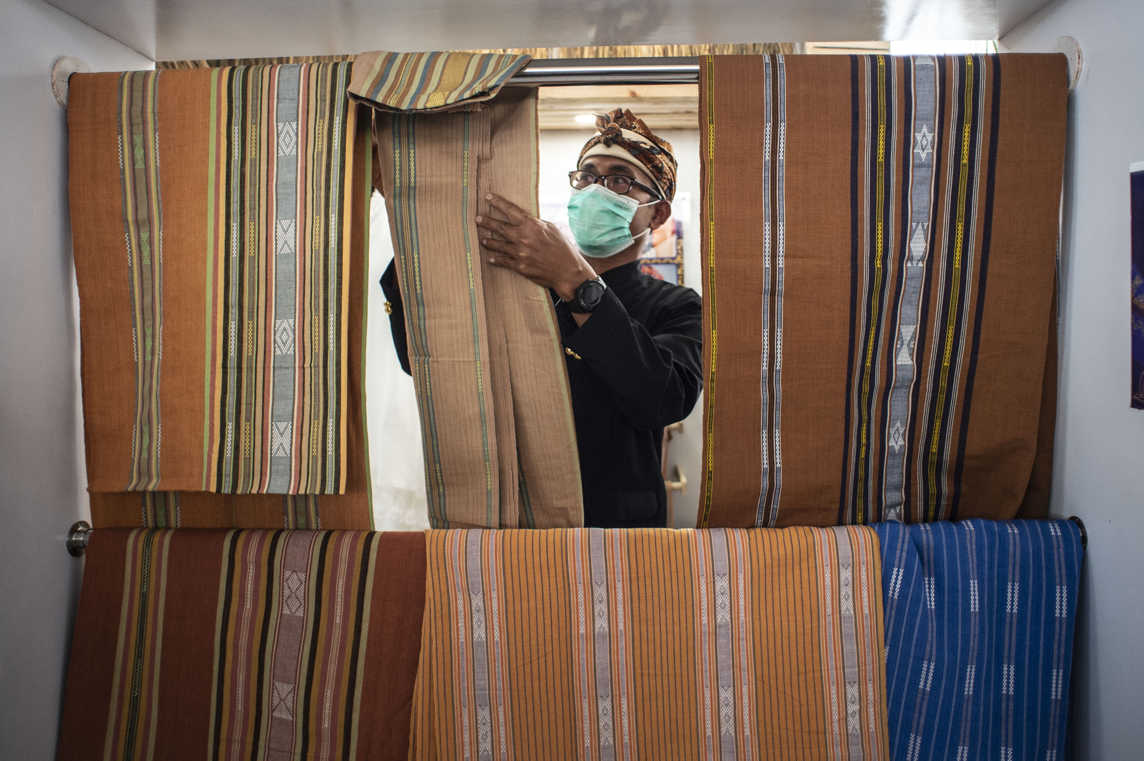 Perajin merapikan tenun buatannya