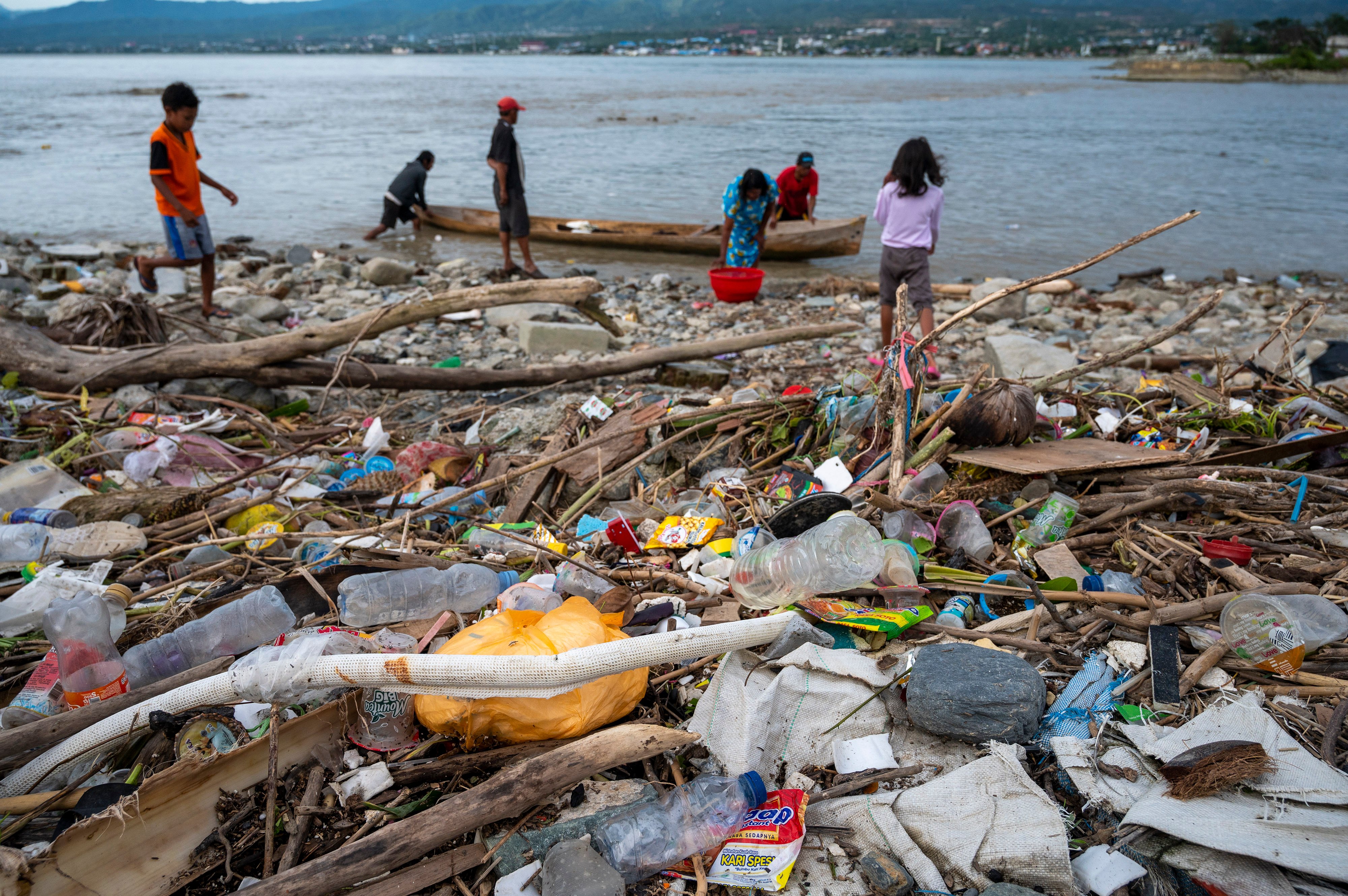 Nelayan beraktivitas di dekat tumpukan sampah plastik yang mencemari muara sungai di Palu, Sulawesi Tengah, tahun lalu.