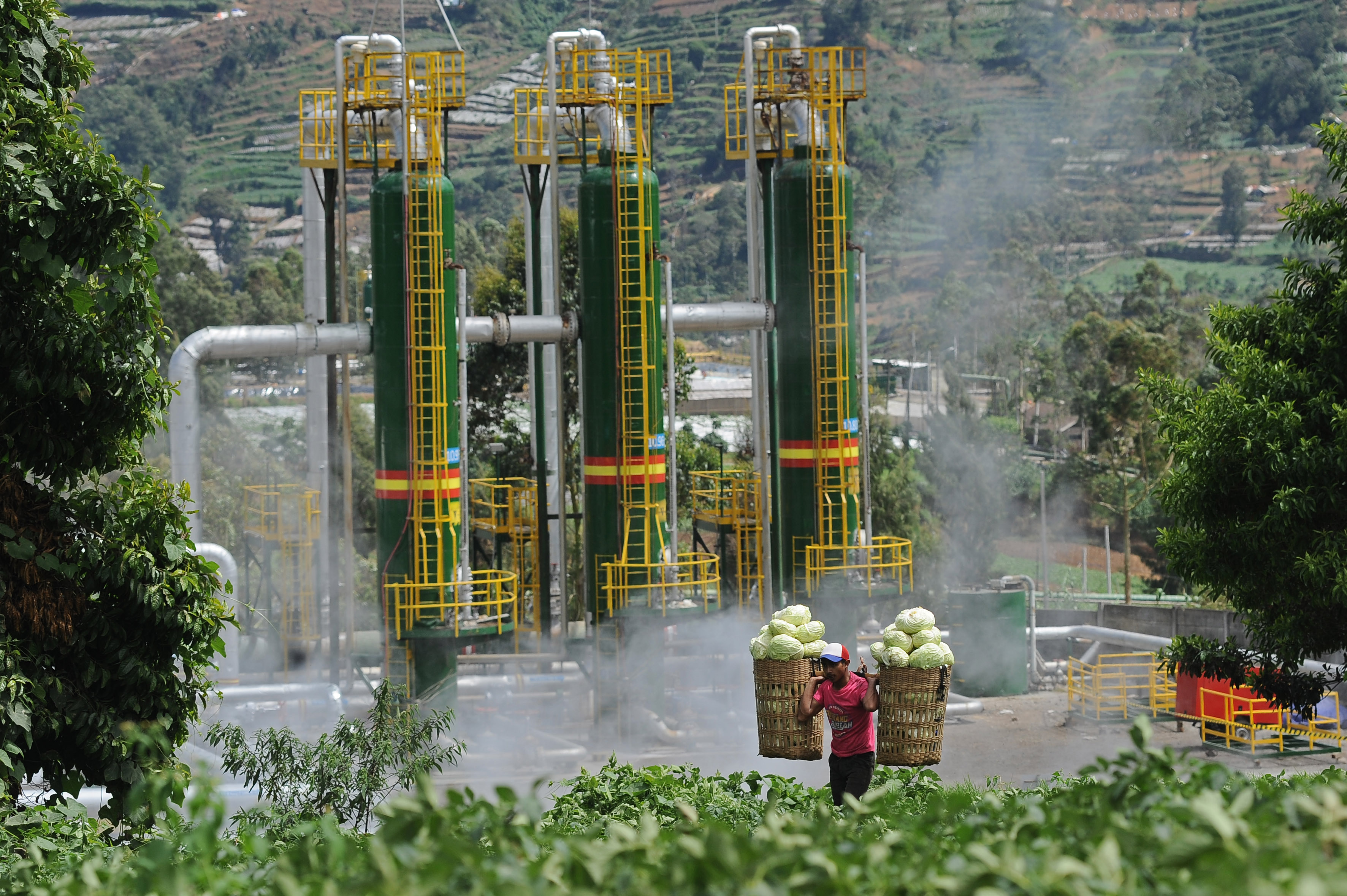 Petani melintasi PLTP milik Geo Dipa di Dieng. Pengembangan panas bumi harus dipandang sebagai beyond electricity.