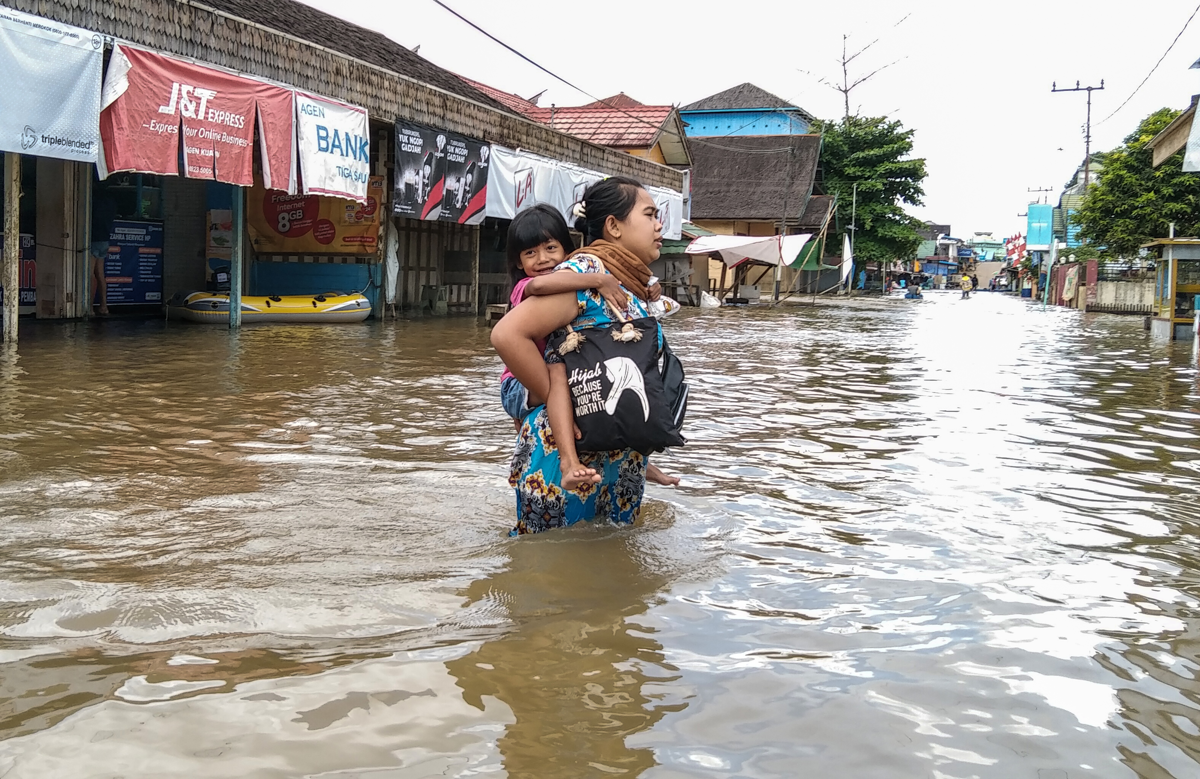 Seorang ibu menggendong anaknya melintasi banjir di permukiman Desa Mentaya Hulu, Kotawaringin Timur, Kalimantan Tengah, Kamis (7/10/2021)