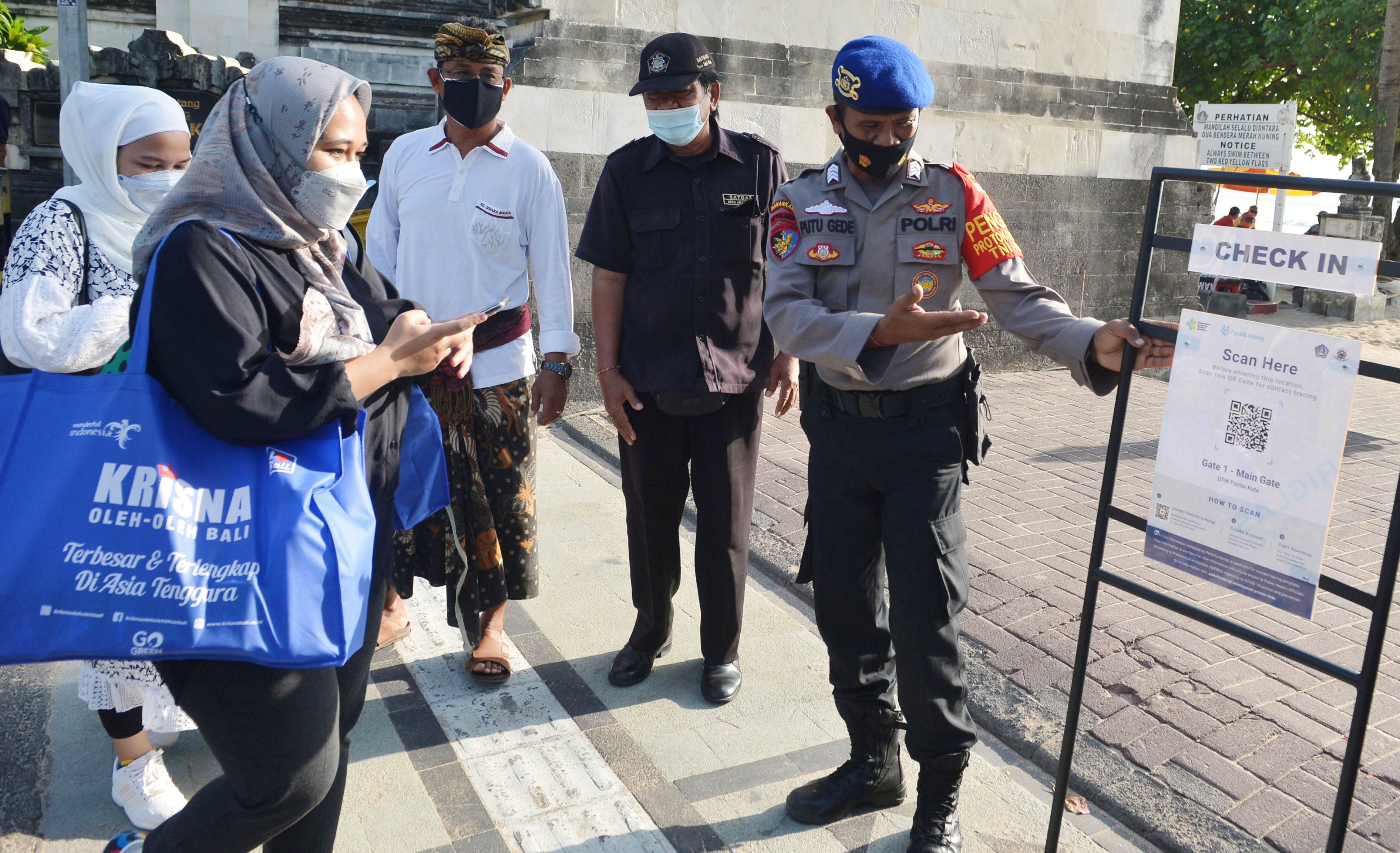Para wisatawan diminta untuk memindai QR Code dengan aplikasi PeduliLindungi sebelum masuk ke Pantai Kuta, Badung, Bali, Minggu (26/9/2021).