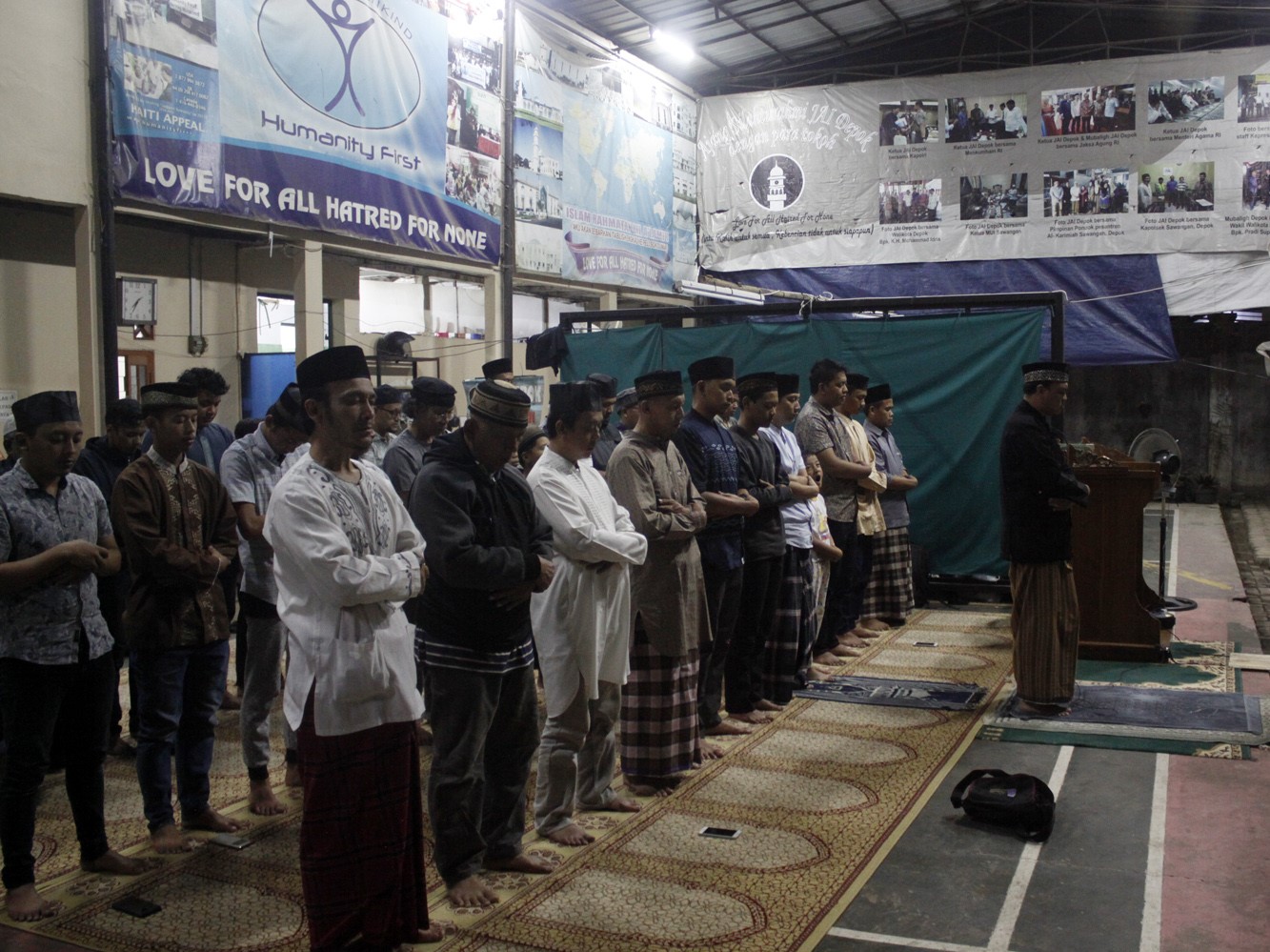 Jemaah Ahmadiyah melaksanakan salat tarawih menghadap pintu Masjid Al Hidayah yang telah disegel di Sawangan, Depok, Jawa Barat.
