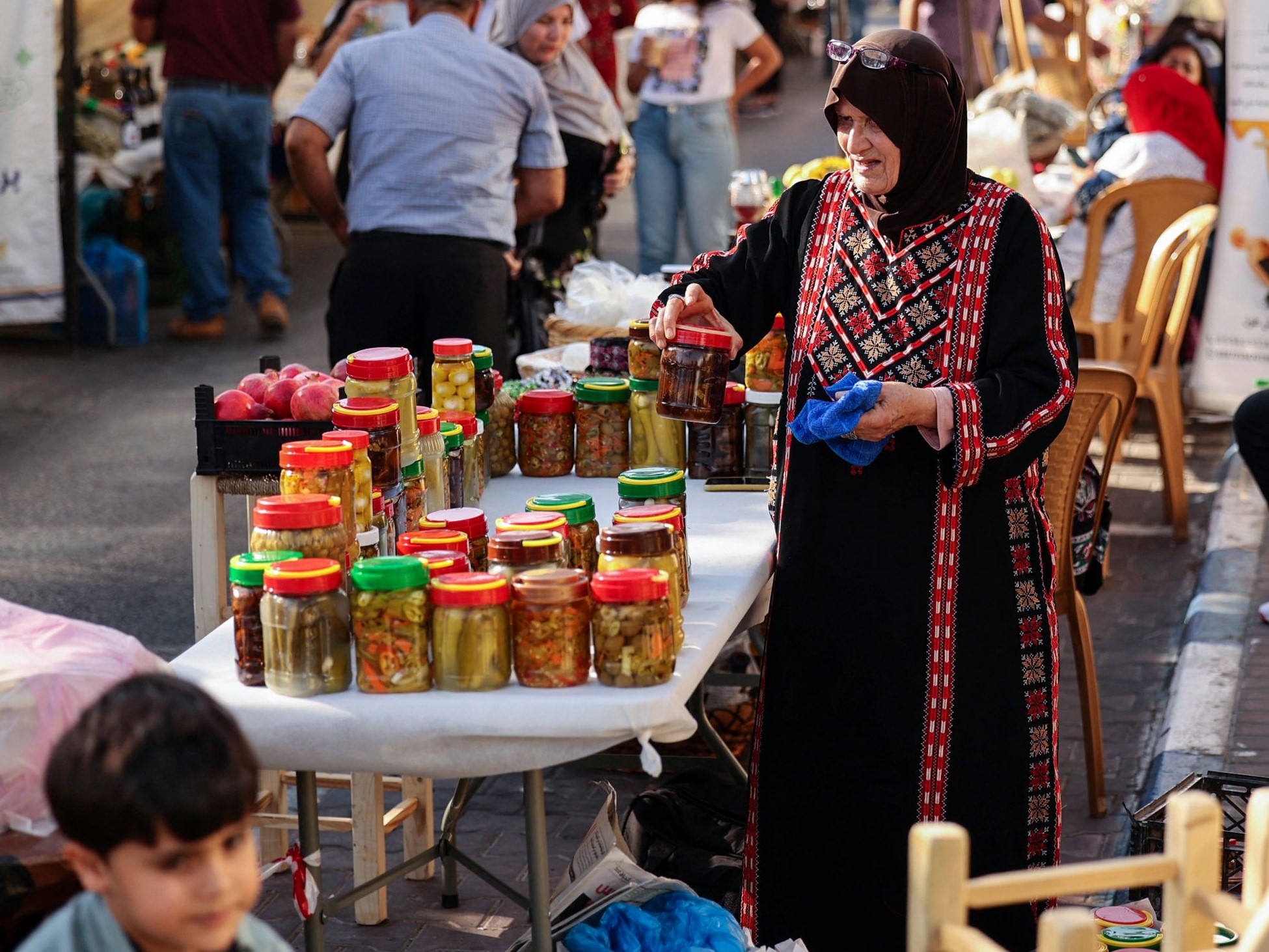 Seorang wanita Palestina dengan pakaian tradisional tatriz (bordir) menjual acar di bazaar belanja dan hiburan, kota Ramallah, Tepi Barat.