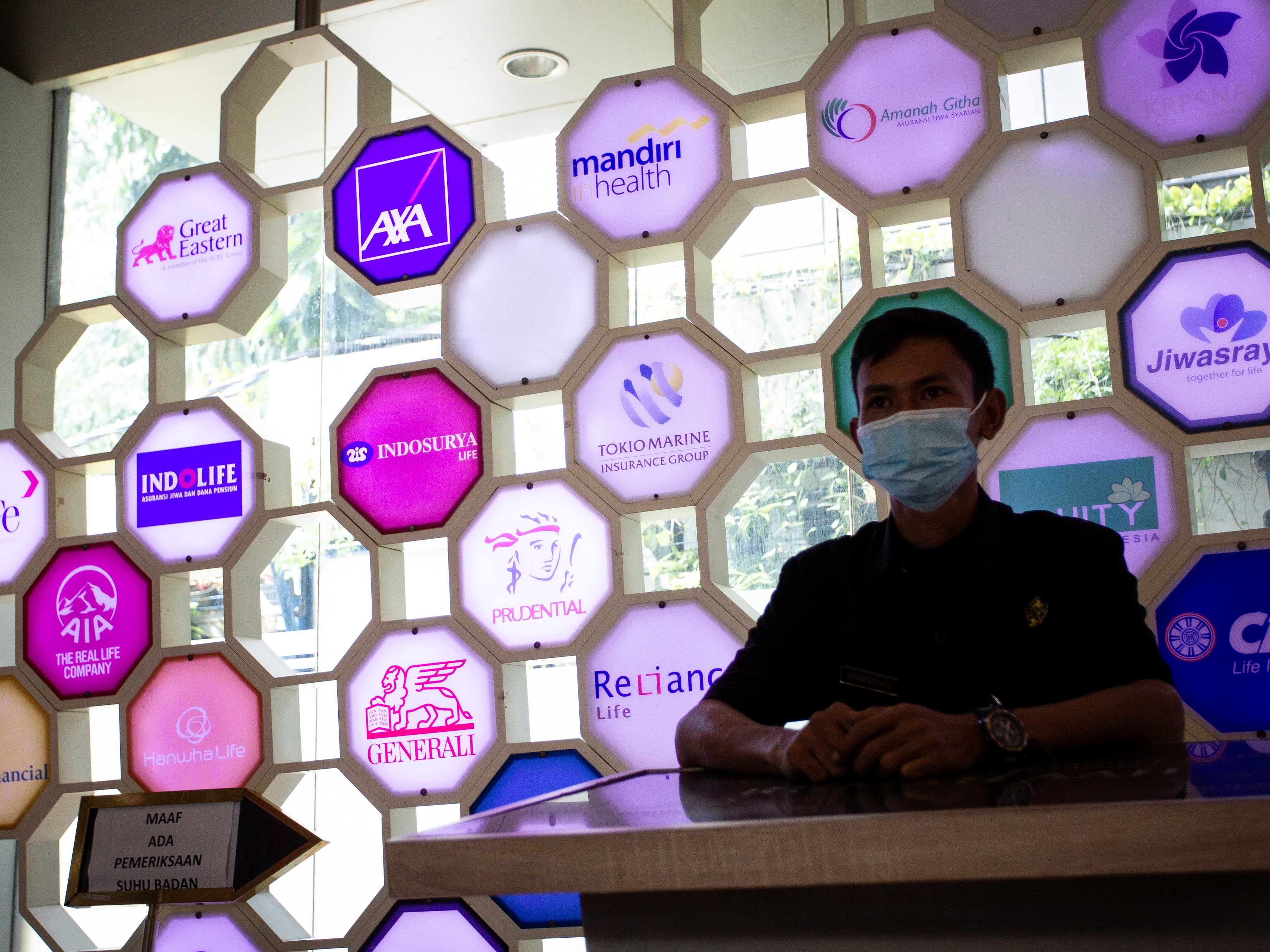 Petugas keamanan bertugas di depan berbagai logo perusahaan asuransi di kantor Asosiasi Asuransi Jiwa Indonesia (AAJI), Jakarta.