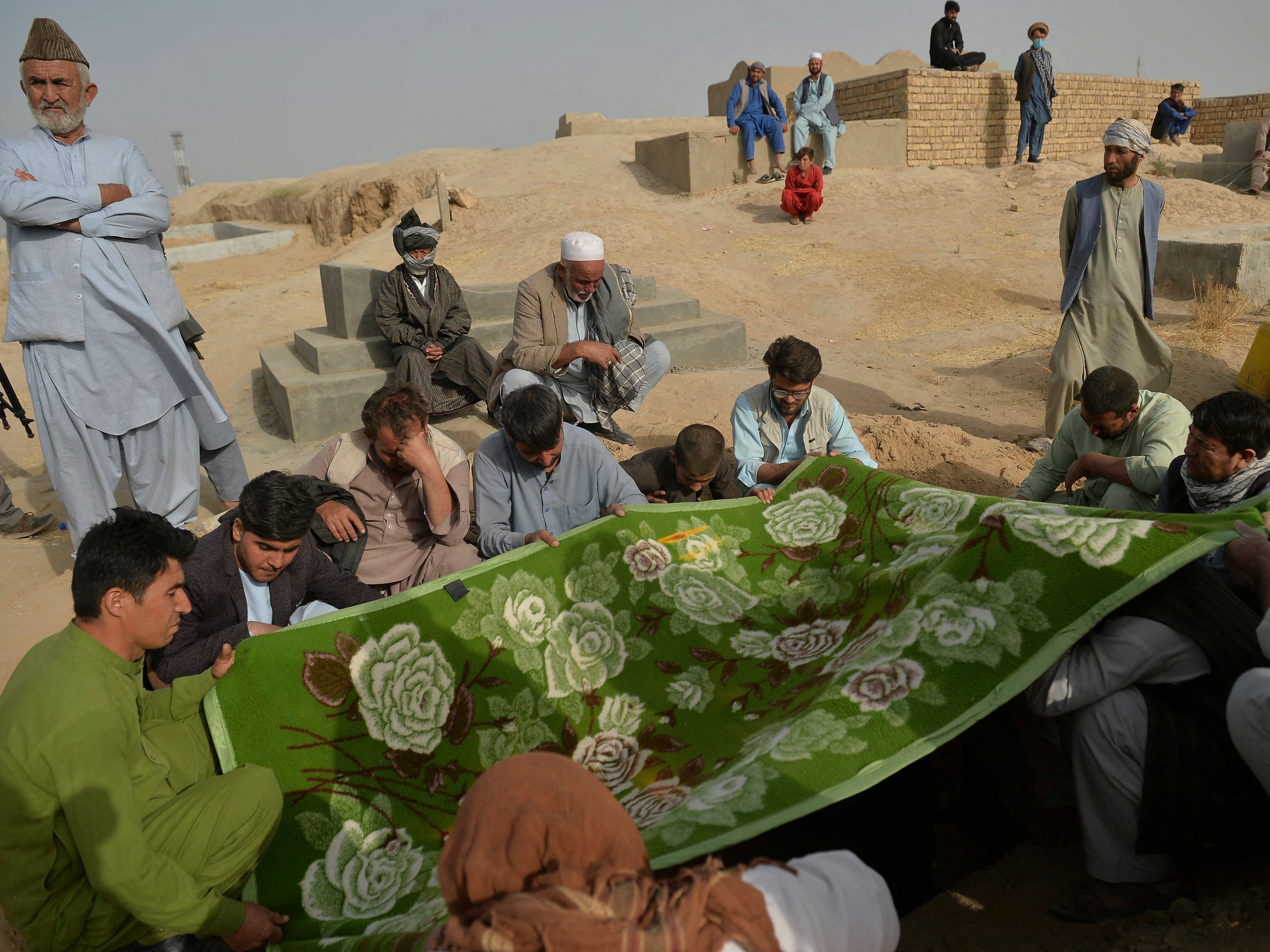 Kerabat dan teman memegang kain yang menutupi kuburan korban serangan bom bunuh diri kemarin terhadap jemaah di masjid Syiah.