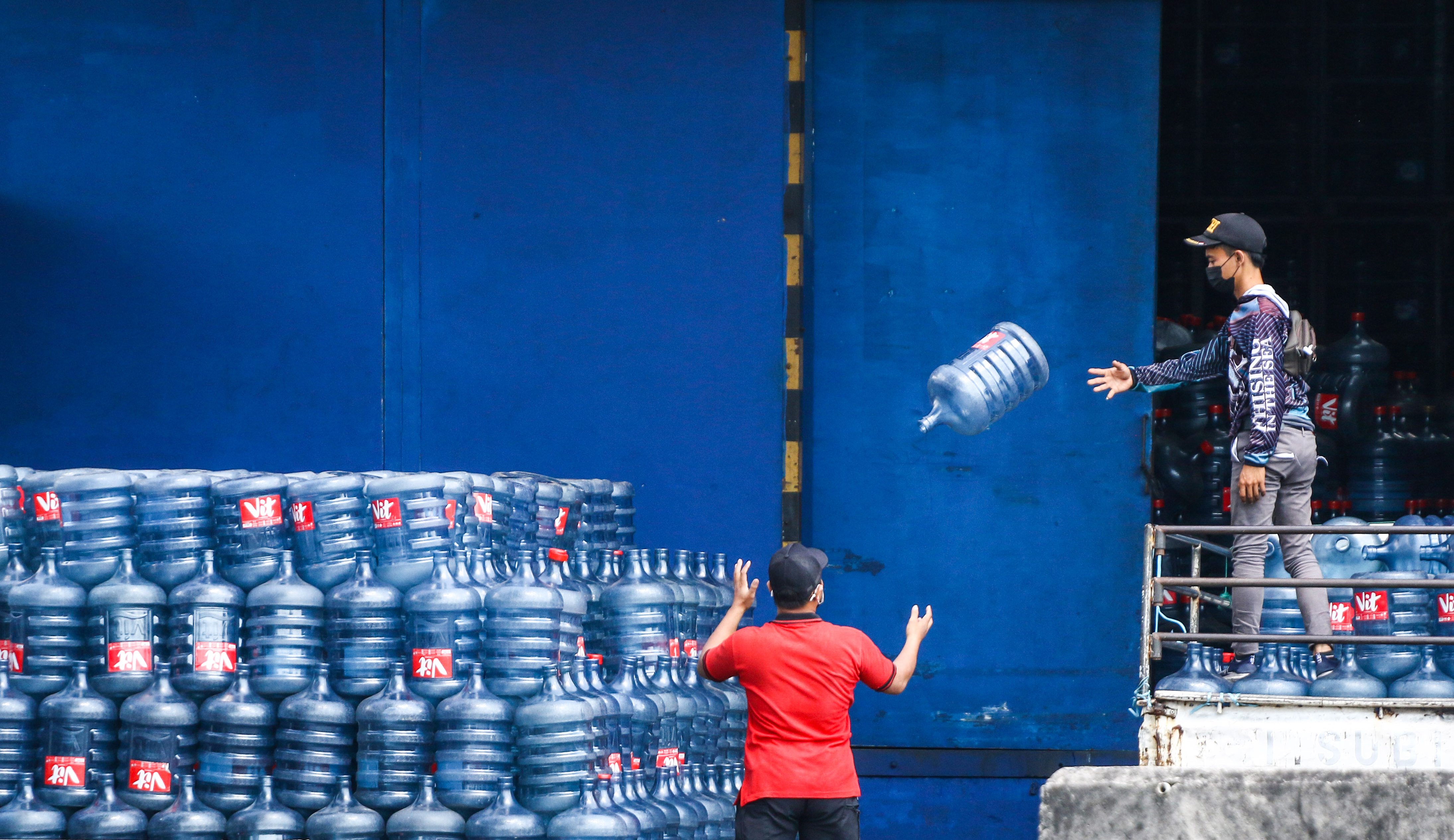 Pekerja memindahkan galon di salah satu depo pengisian air minum dalam kemasan.