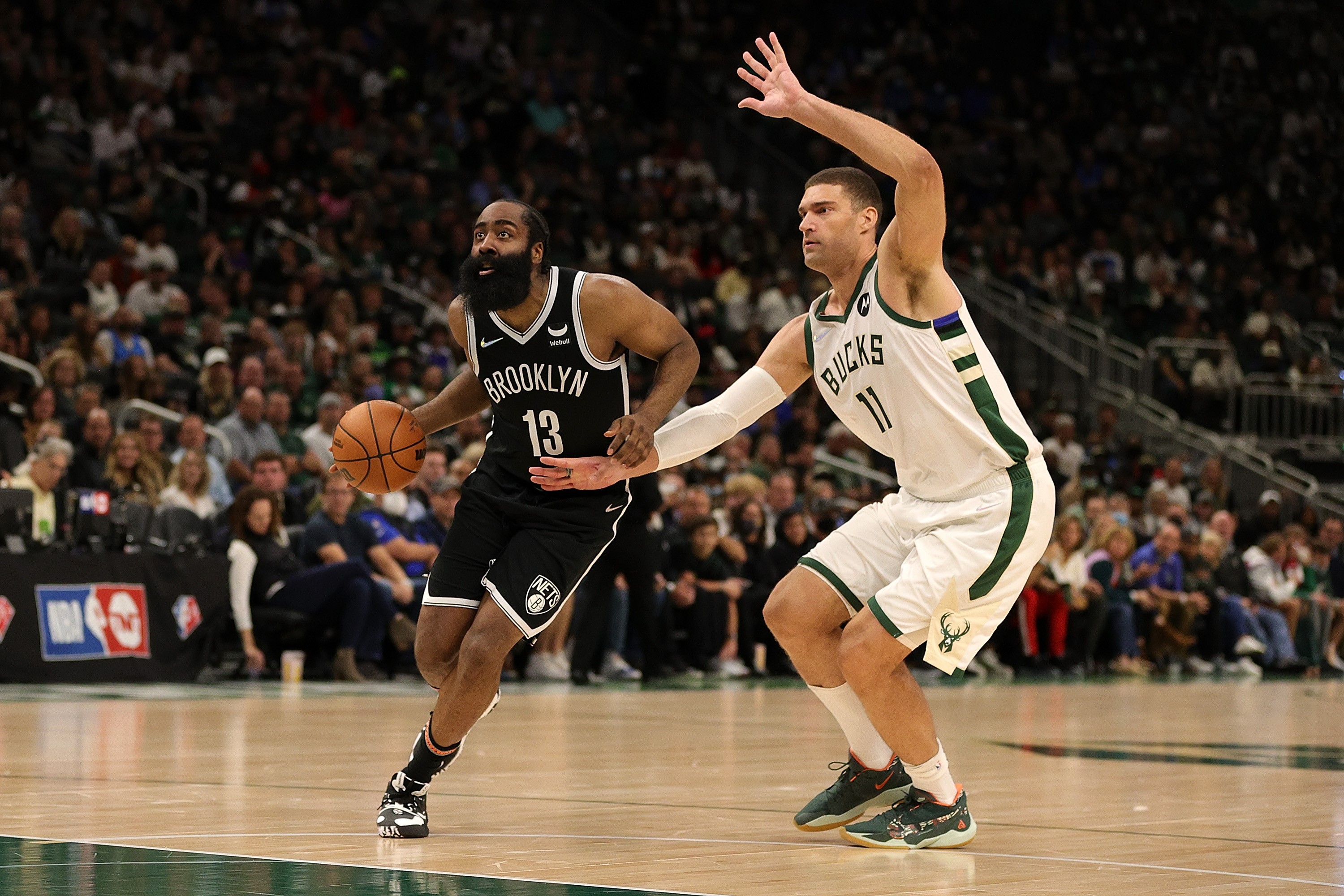 James Harden (kiri) dari Brooklyn Nets menggiring bola dengan dibayangi Brook Lopez dari Milwaukee Bucks. 