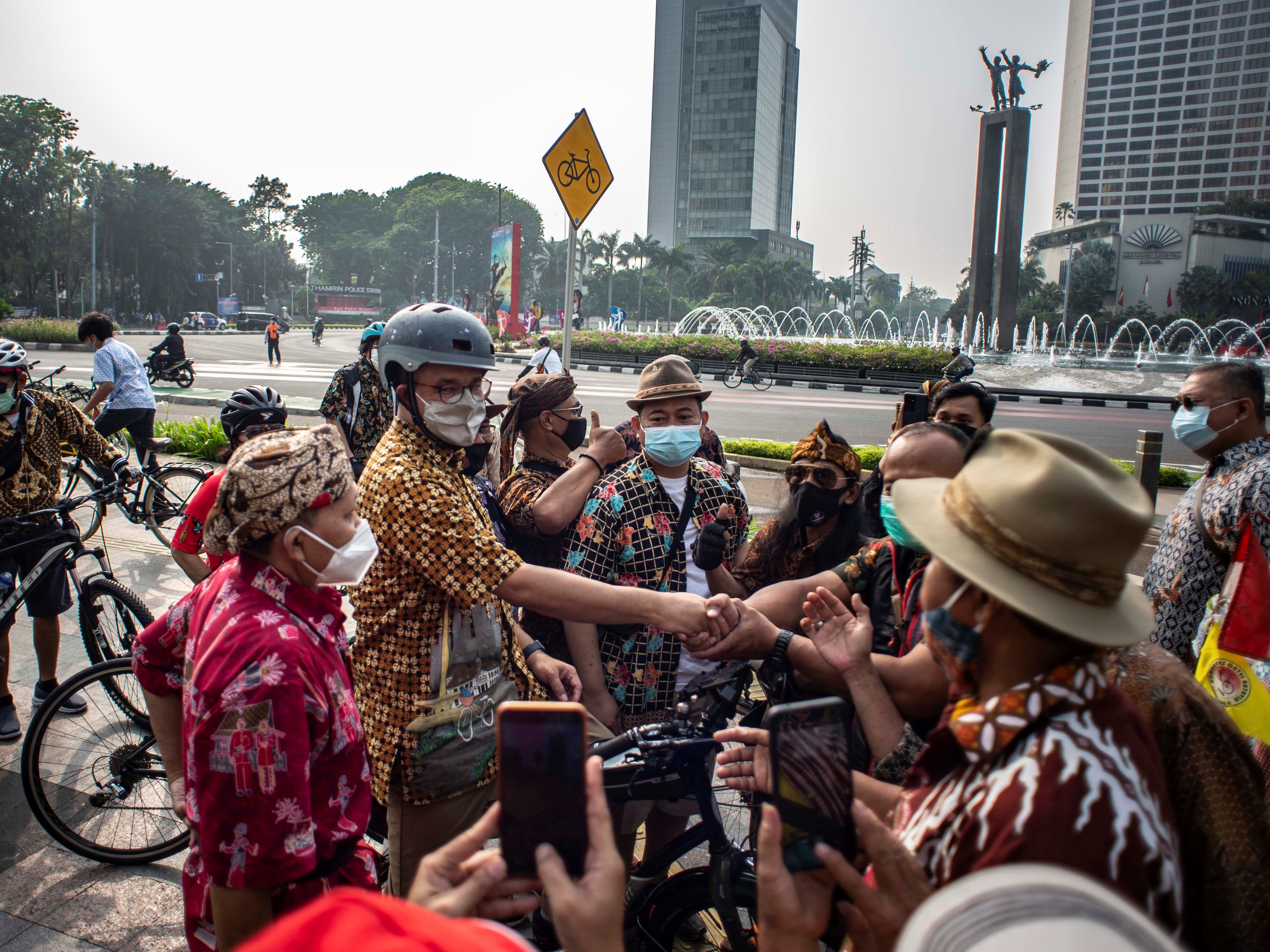 Gubernur DKI Jakarta Anies Baswedan (kiri) mengenakan baju batik saat menyapa para pesepeda di kawasan Bundaran HI, Jakarta, Sabtu (2/10).