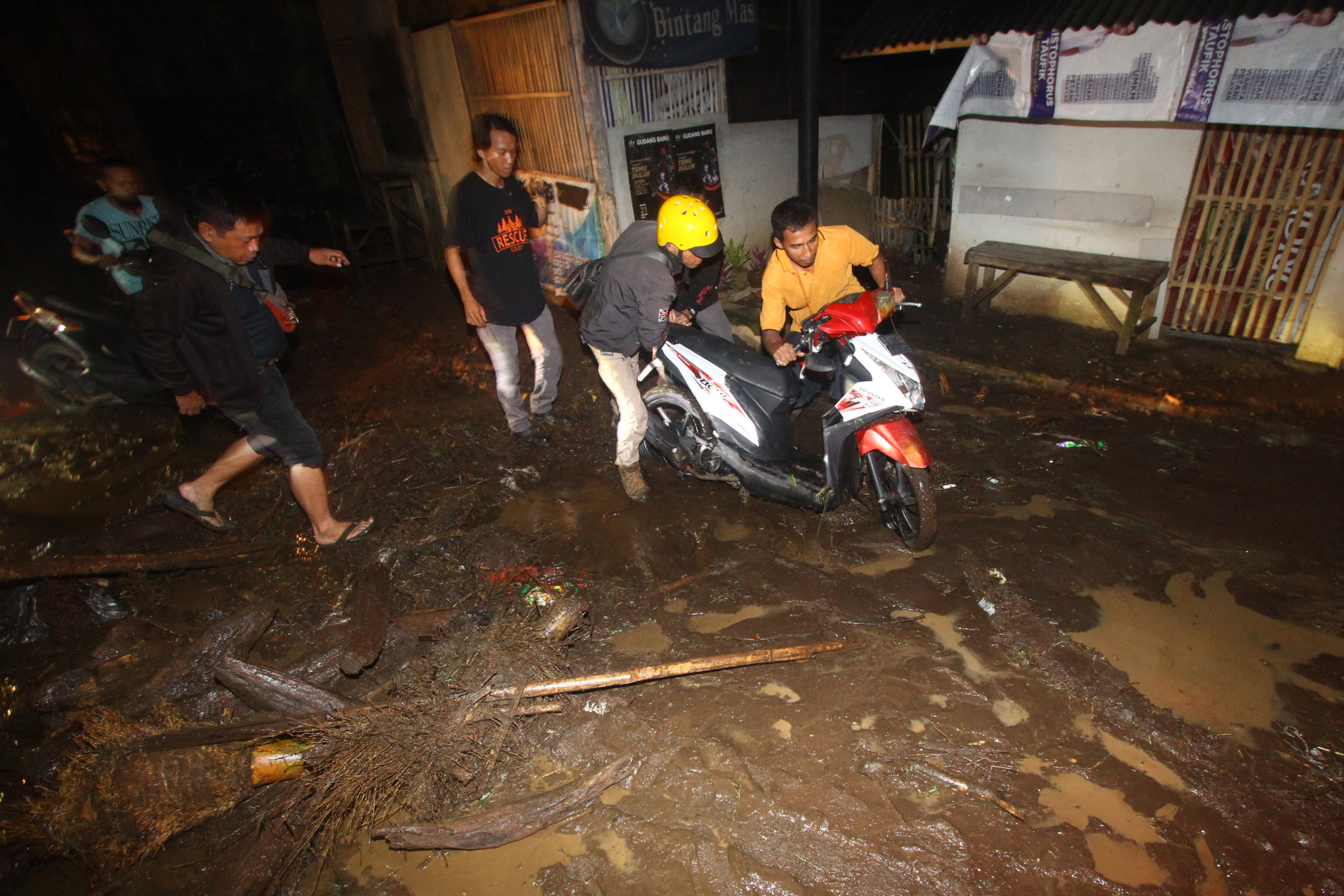  Warga membantu pengendara motor melintas di jalan berlumpur saat terjadi banjir bandang di Petungsewu, Dau, Malang, Jumat (24/1/2020)