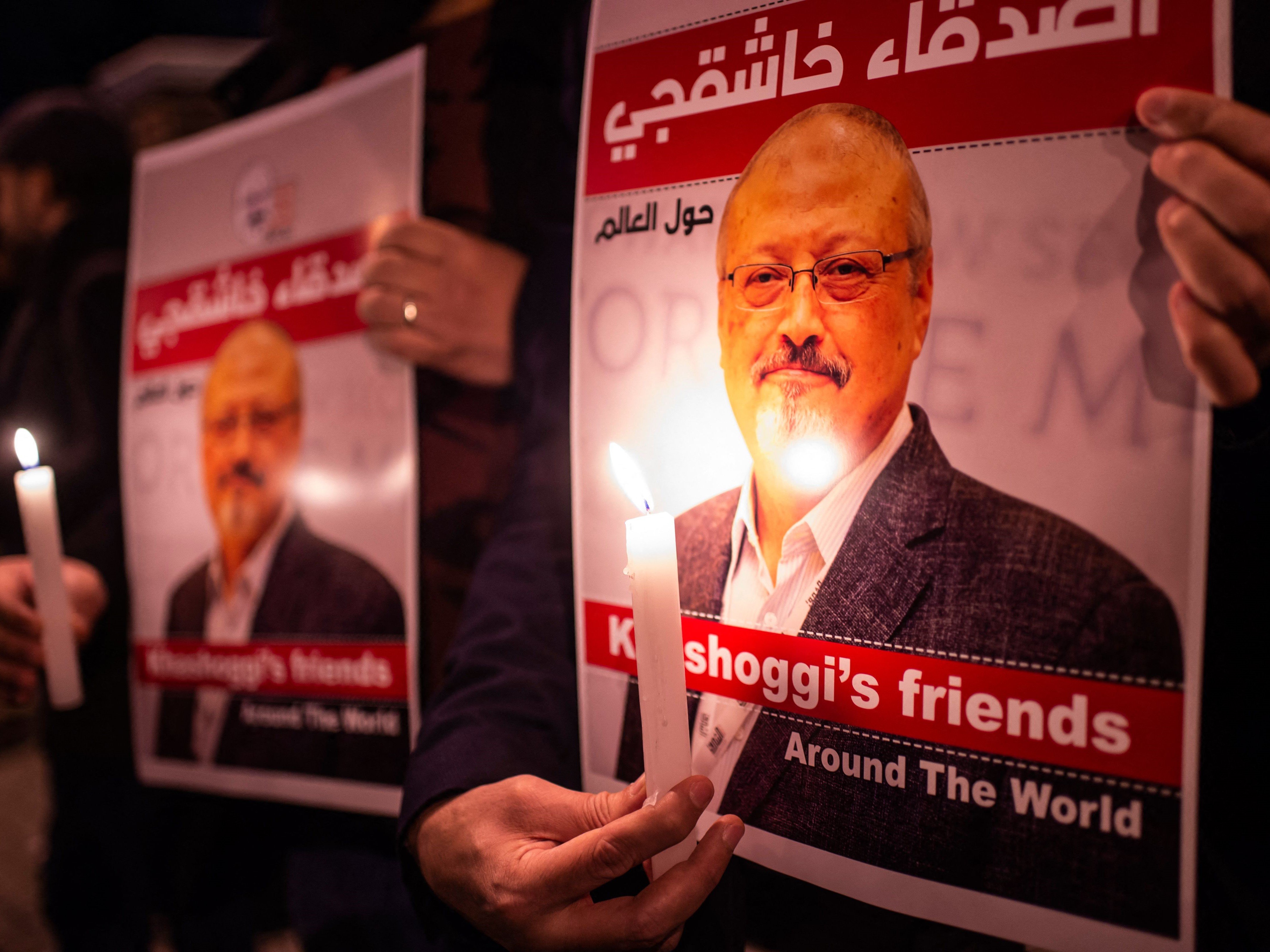Orang-orang memegang poster bergambar jurnalis Saudi Jamal Khashoggi dan menyalakan lilin di luar konsulat Arab Saudi, Istanbul, Turki.
