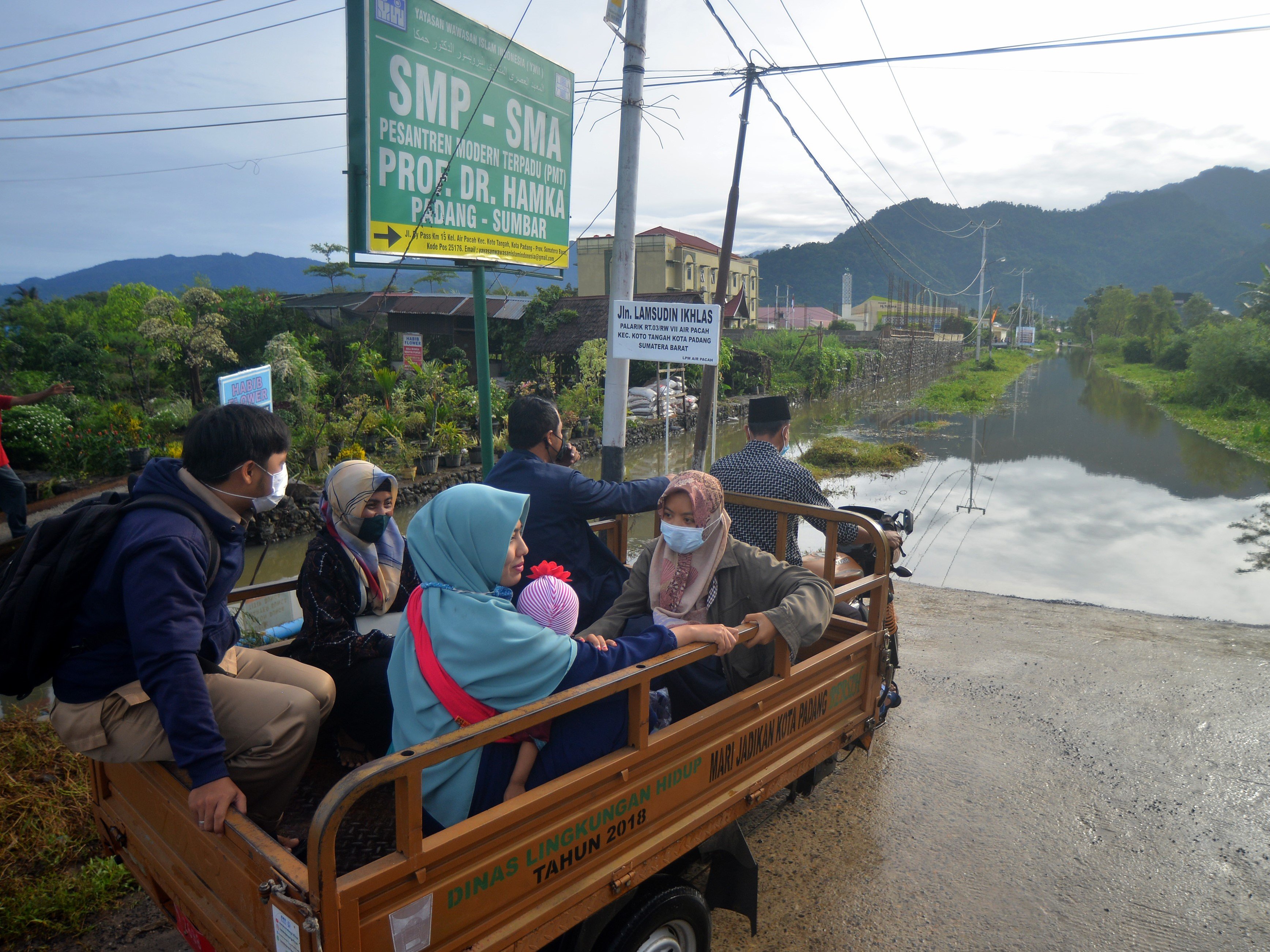 Sejumlah staf dan pengajar diangkut menggunakan gerobak motor menuju pesantren karena jalan terendam banjir, Aia Pacah, Padang, Sumbar.