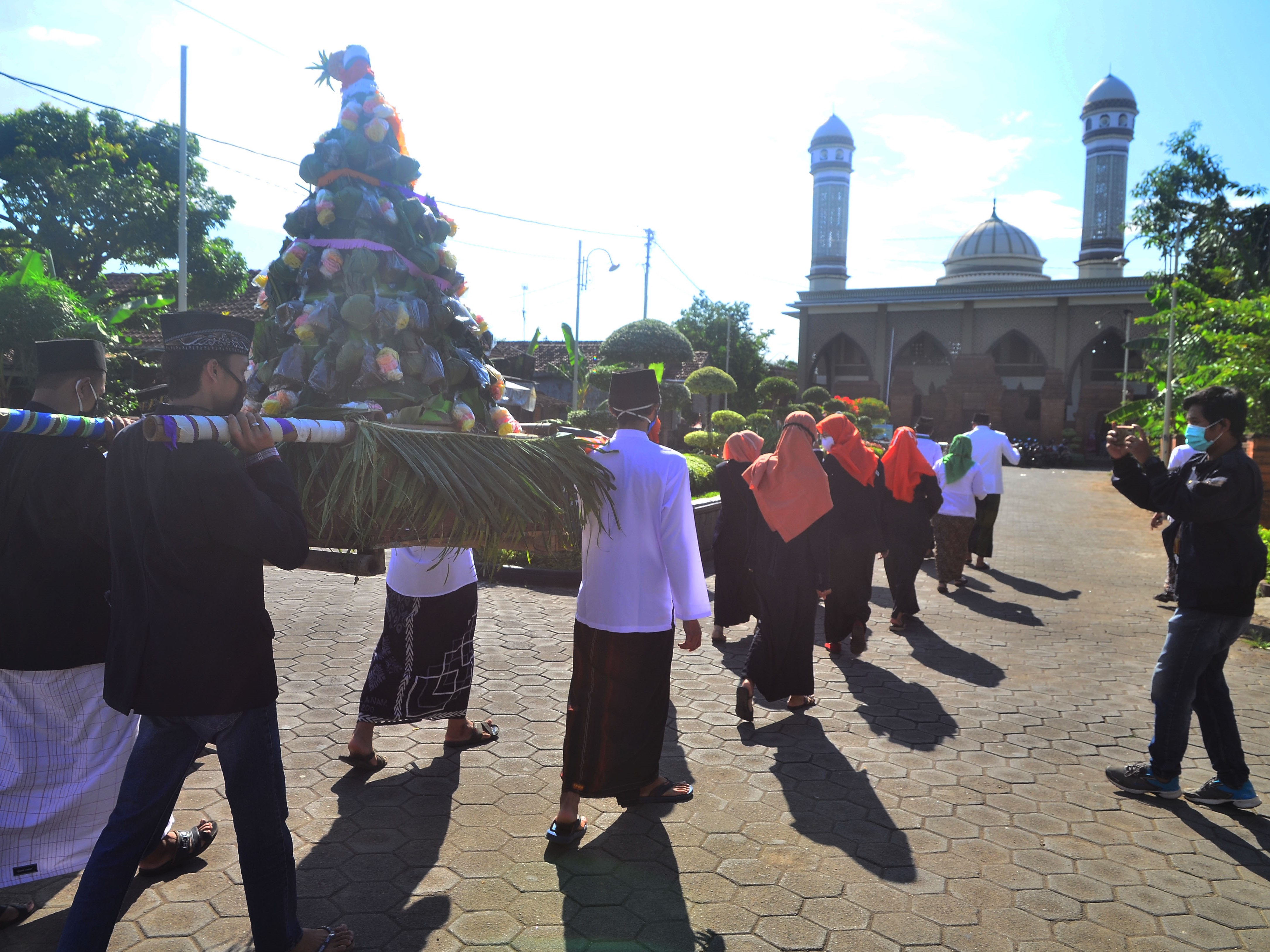 Warga memikul gunungan berisi nasi yang dibungkus daun jati saat tradisi Ampyang Maulid di Desa Loram Kulon, Jati, Kudus, Jawa Tengah.