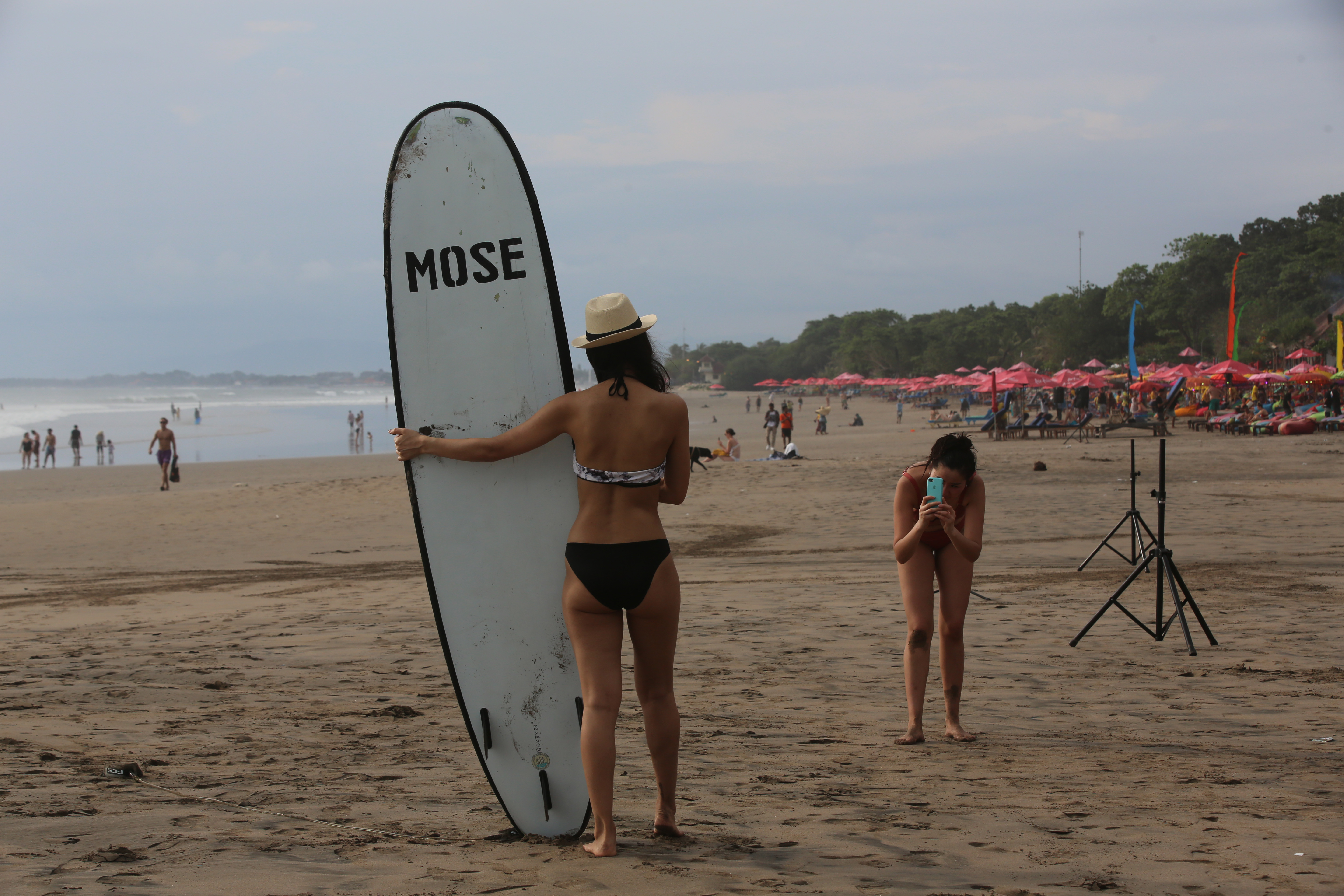 Wistawan asing berfoto menikmati pantai menjelang matahari terbenam di Pantai Seminyak, Bali.