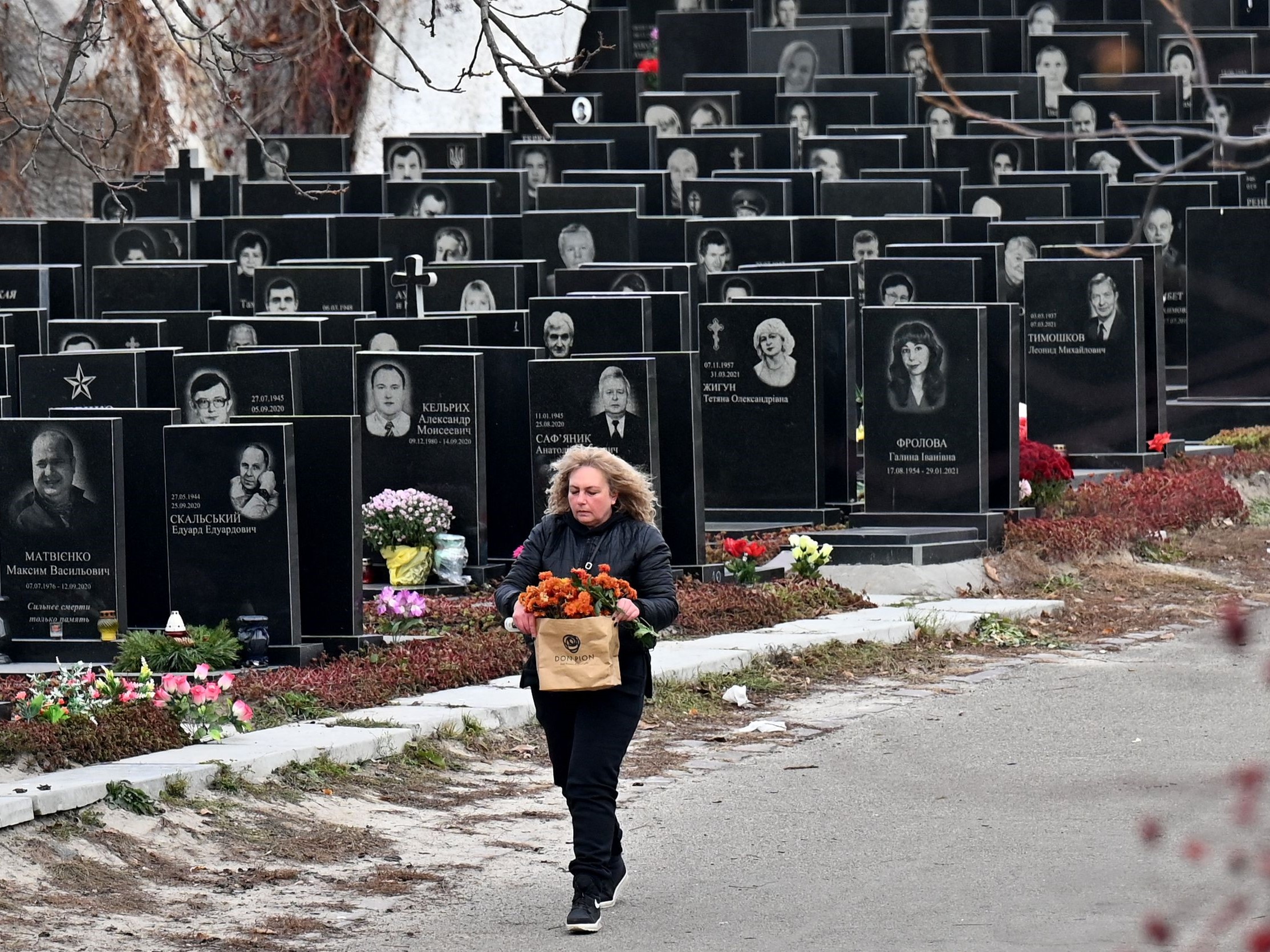 Seorang wanita berjalan di pemakaman di Kiev pada 11 November 2021, di tengah pandemi penyakit covid-19.