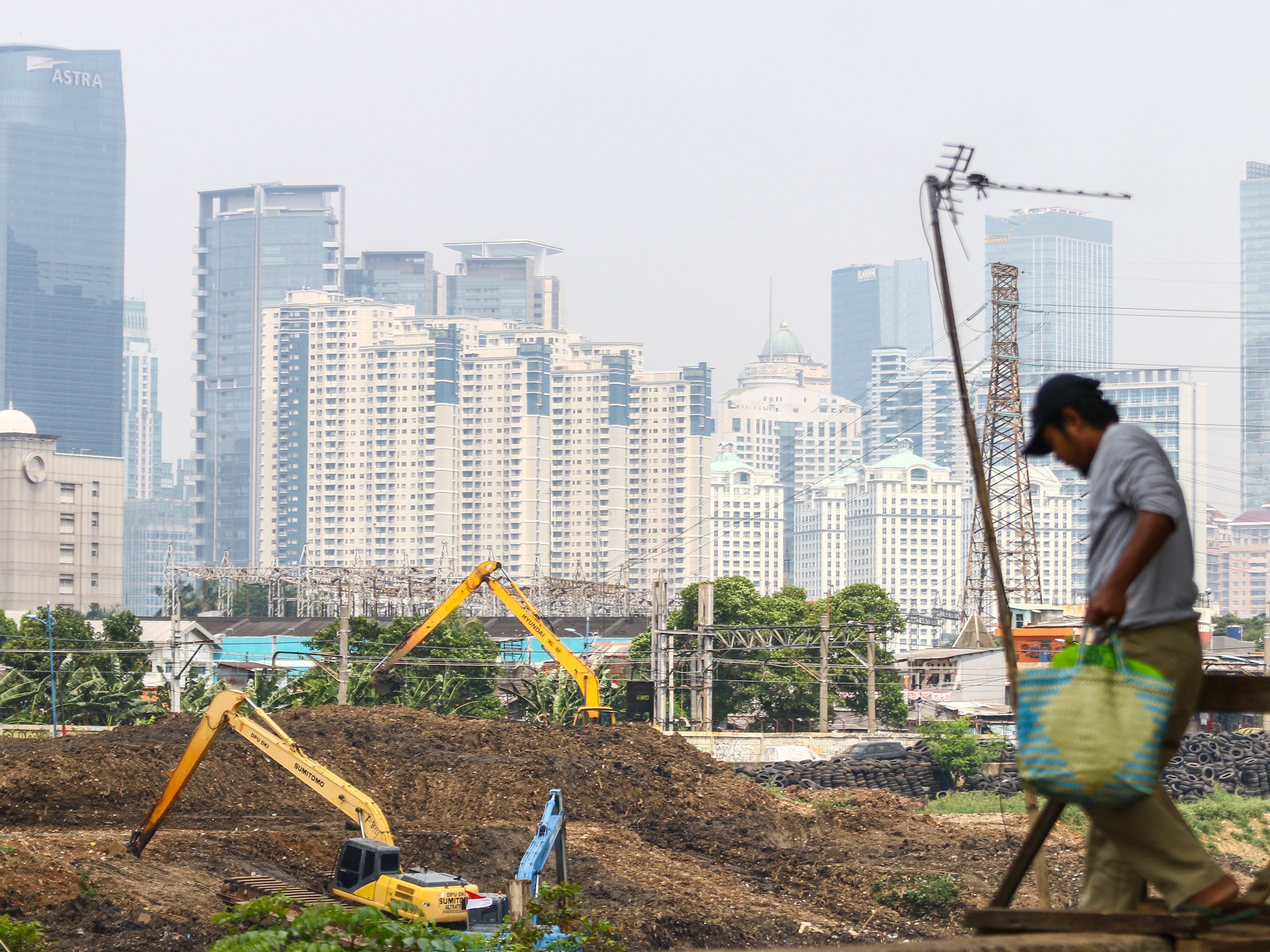 Warga melintas dengan latar belakang gedung bertingkat di Jakarta, Kamis (26/8/2021).