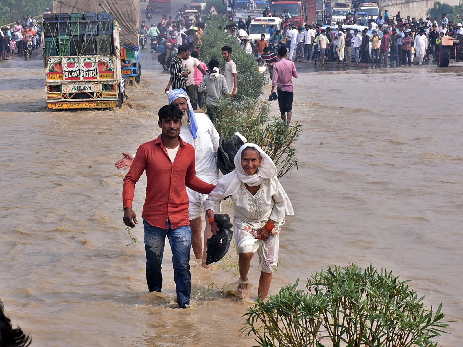 Warga mengarungi jalan raya nasional yang banjir setelah sungai Kosi meluap menyusul hujan lebat, Uttar Pradesh, India, Rabu (20/10). 
