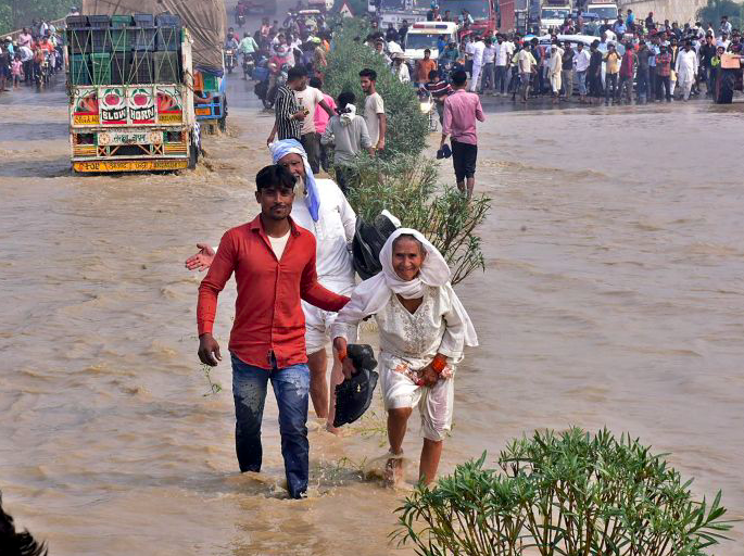 Warga mengarungi jalan raya nasional yang banjir setelah sungai Kosi meluap menyusul hujan lebat, Uttar Pradesh, India, Rabu (20/10). 